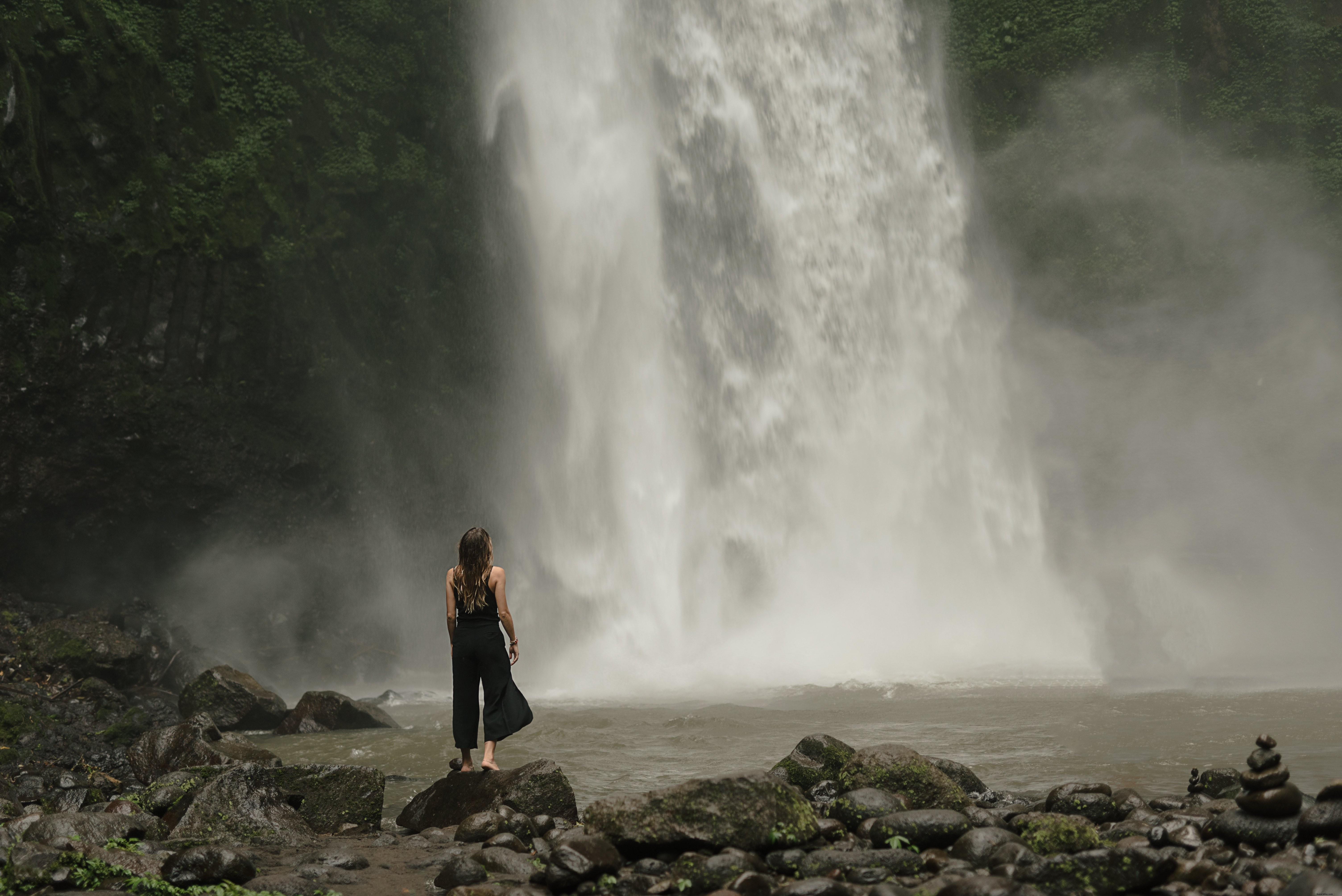 Stunning Photo: Woman Pauses at the Foot of a Majestic Waterfall