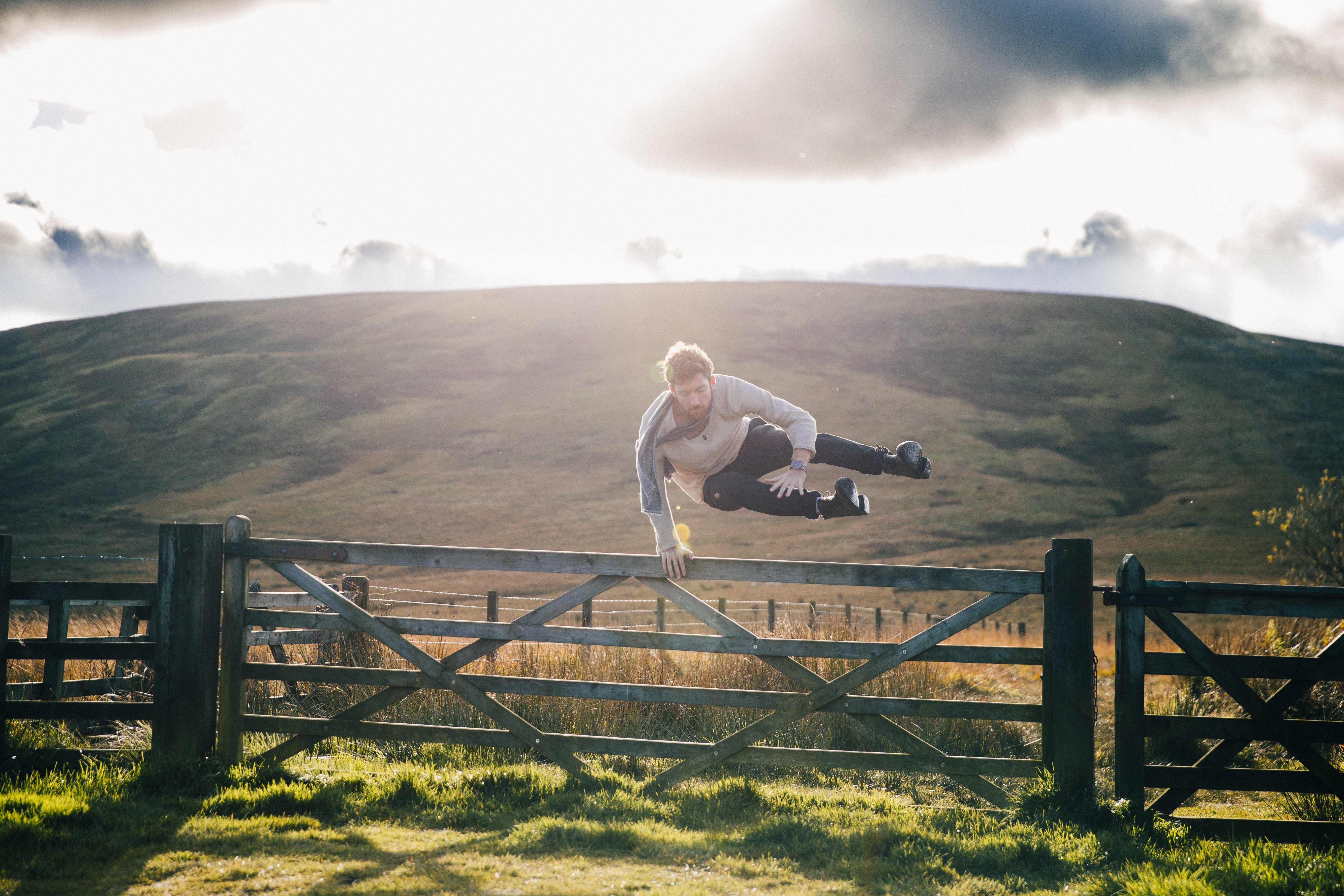 Dynamic Photo: Man Leaping Over Fence in Scenic Field