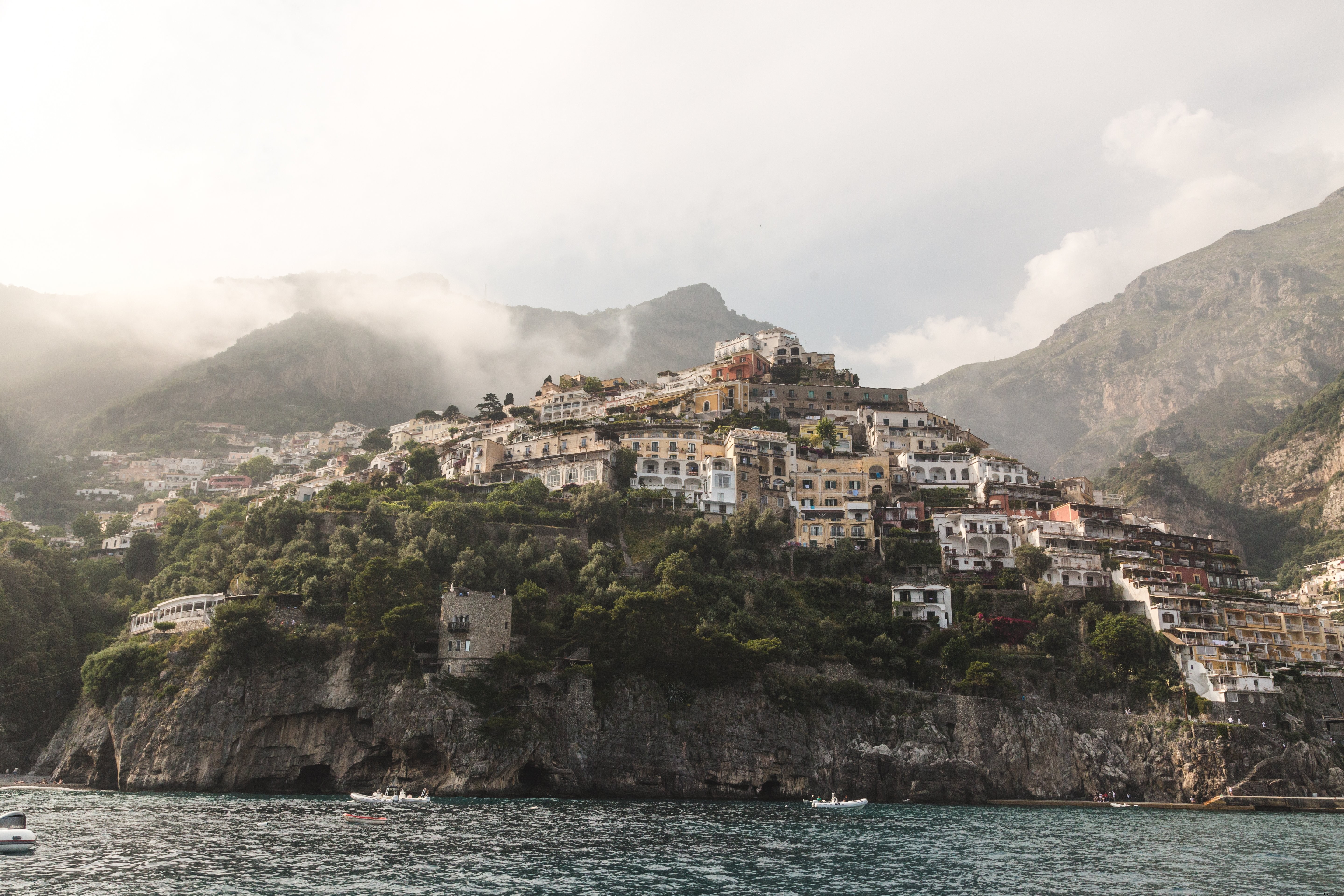 Stunning Surreal Photo: Boats Sailing Beneath Buildings on Dramatic Rock Face