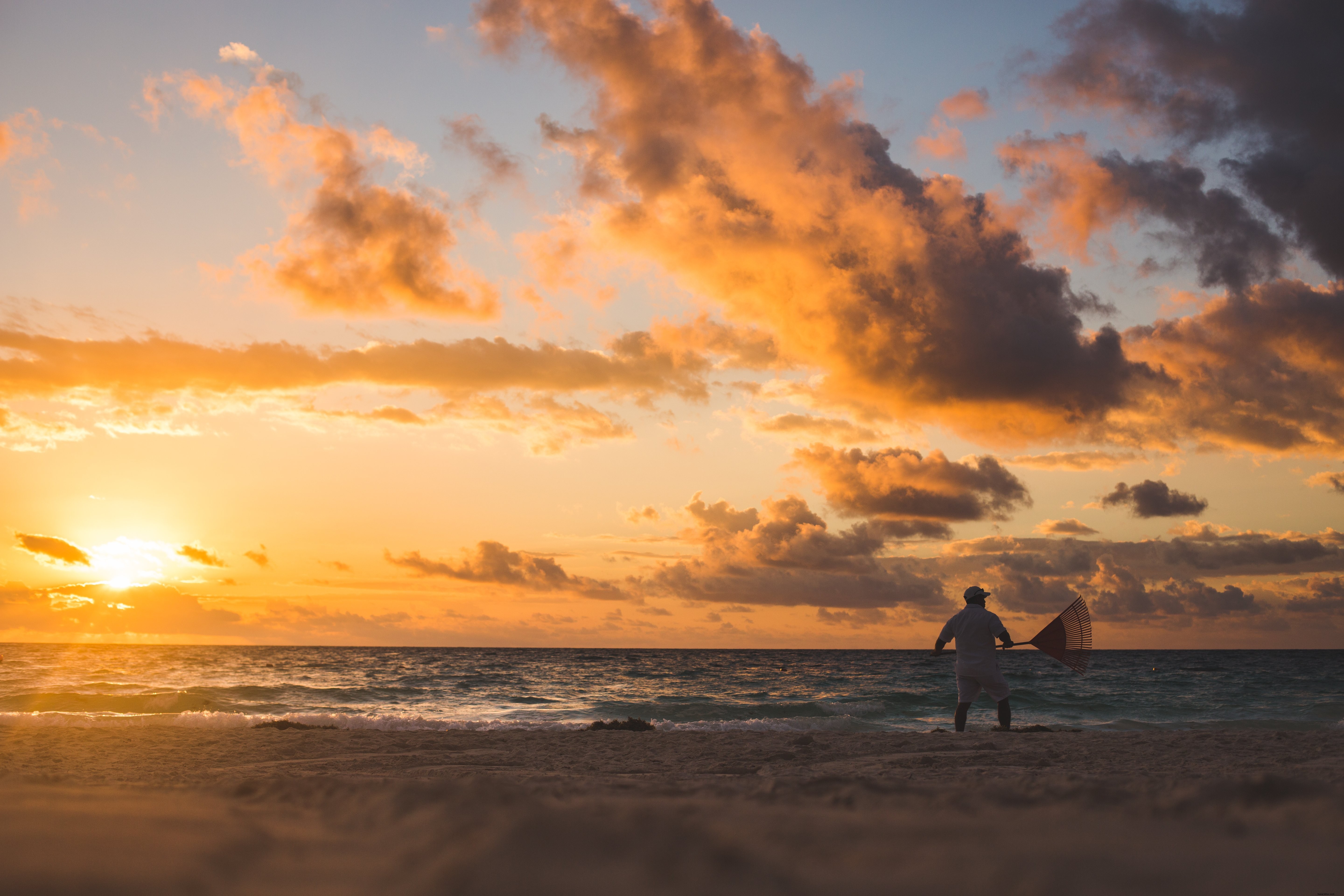 Man Raking Beach at Sunset: Stunning Scenic Photography