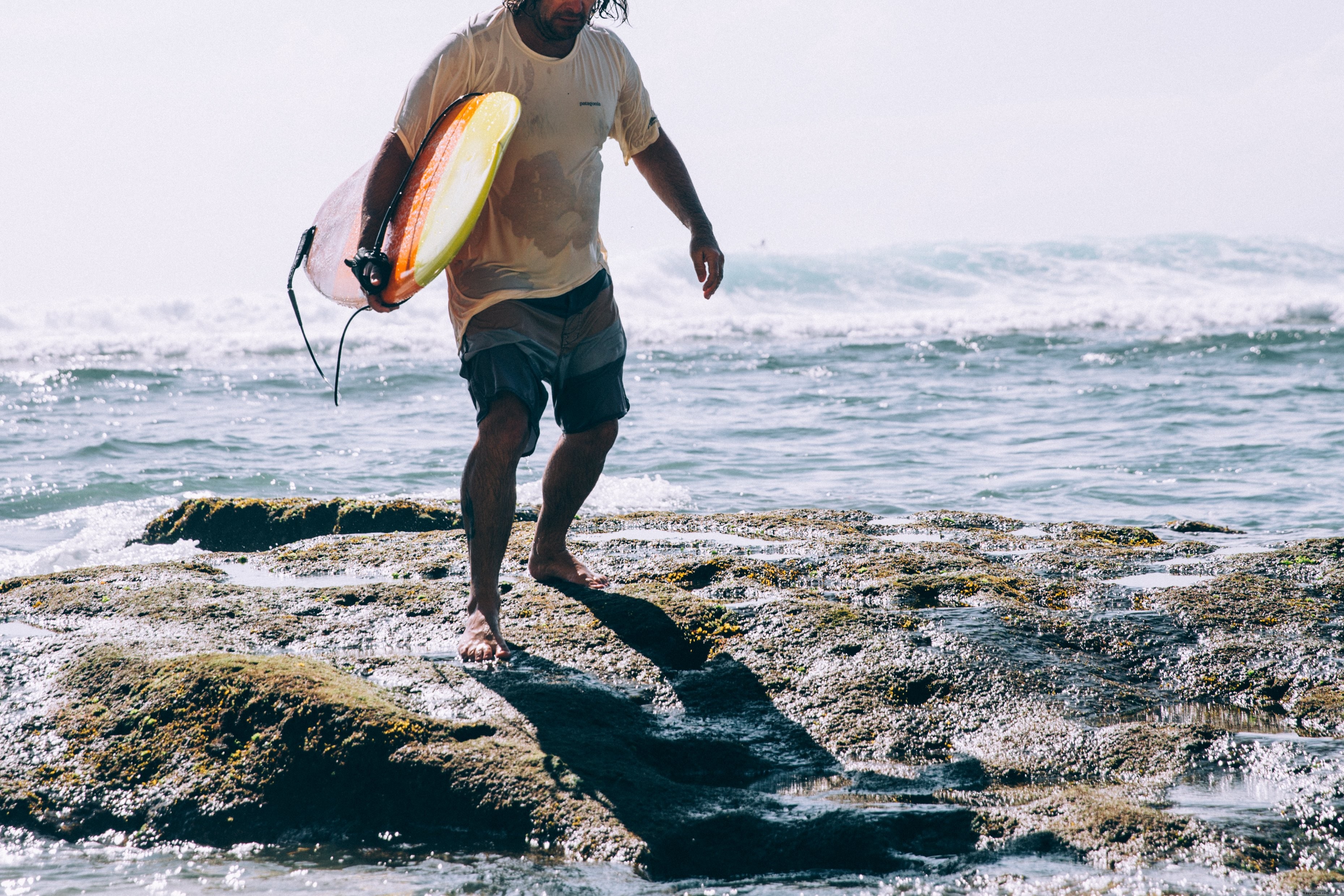 Stunning Photo: Surfer Emerges from Crashing Ocean Waves Carrying Surfboard