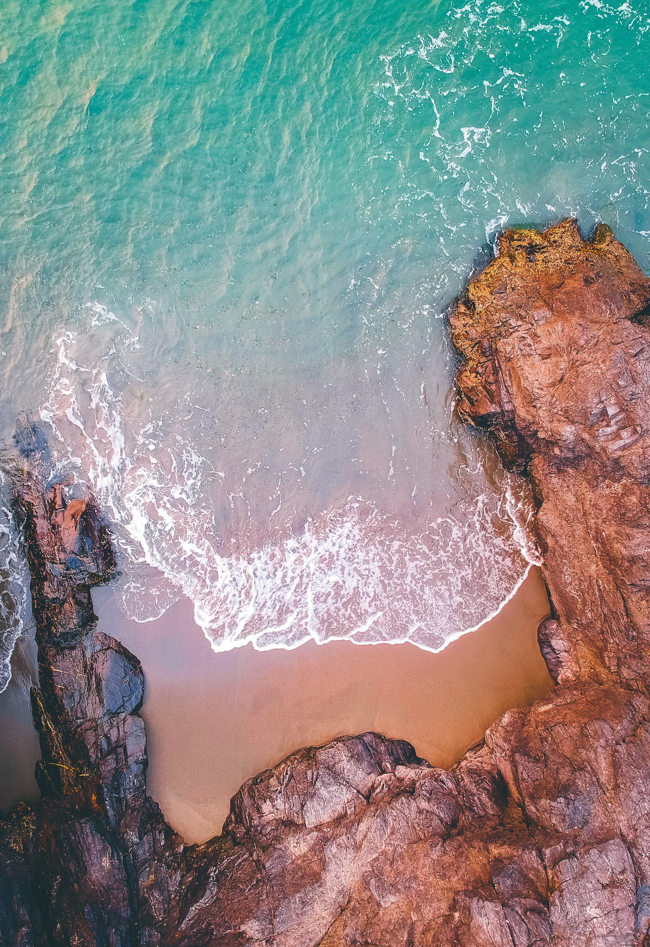 Stunning Aerial View: Ocean Waves Crashing on Rocky Shore