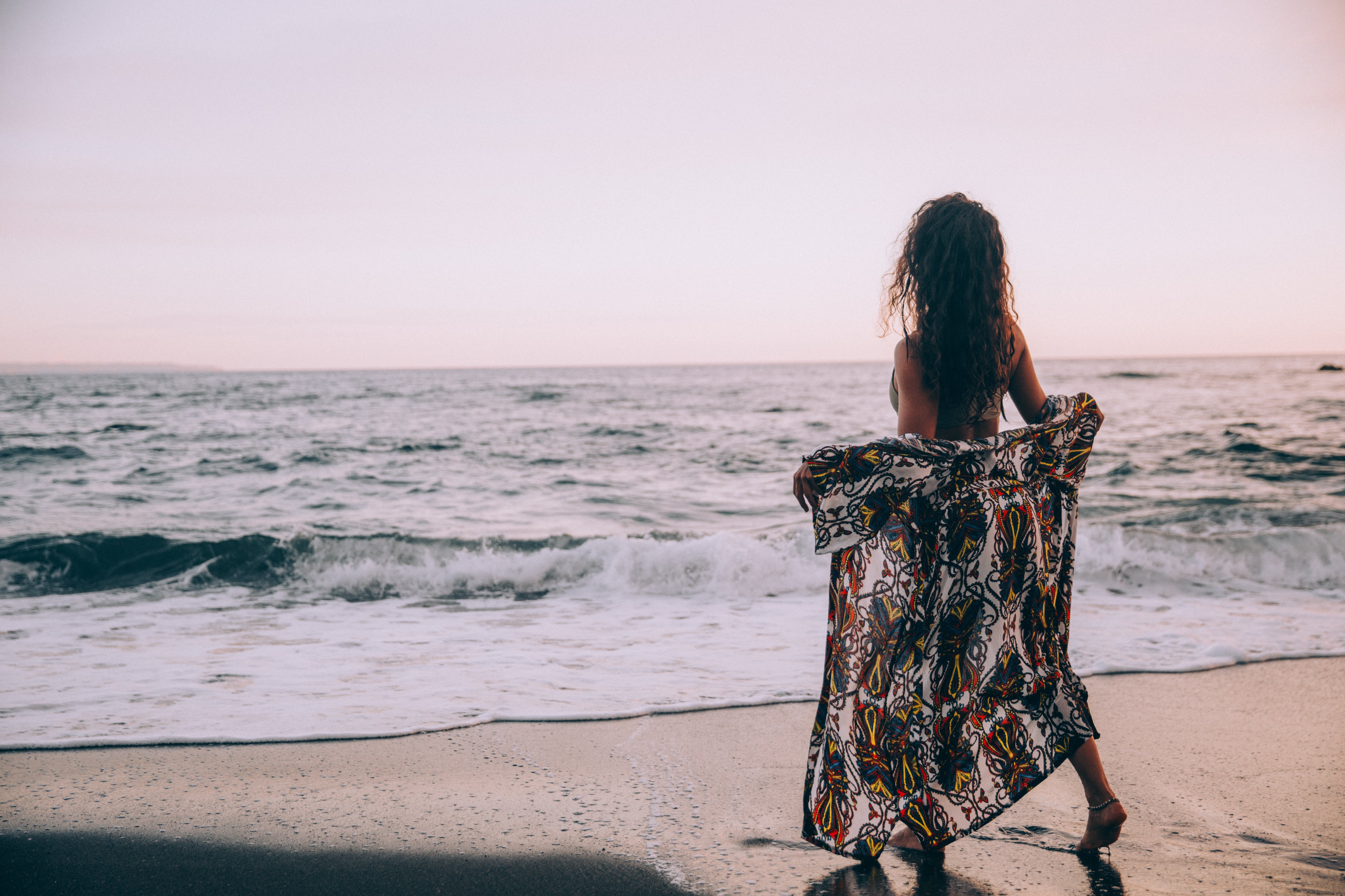 Stunning Beach Photo: Woman Gracefully Unveils Sarong Amid Rolling Waves