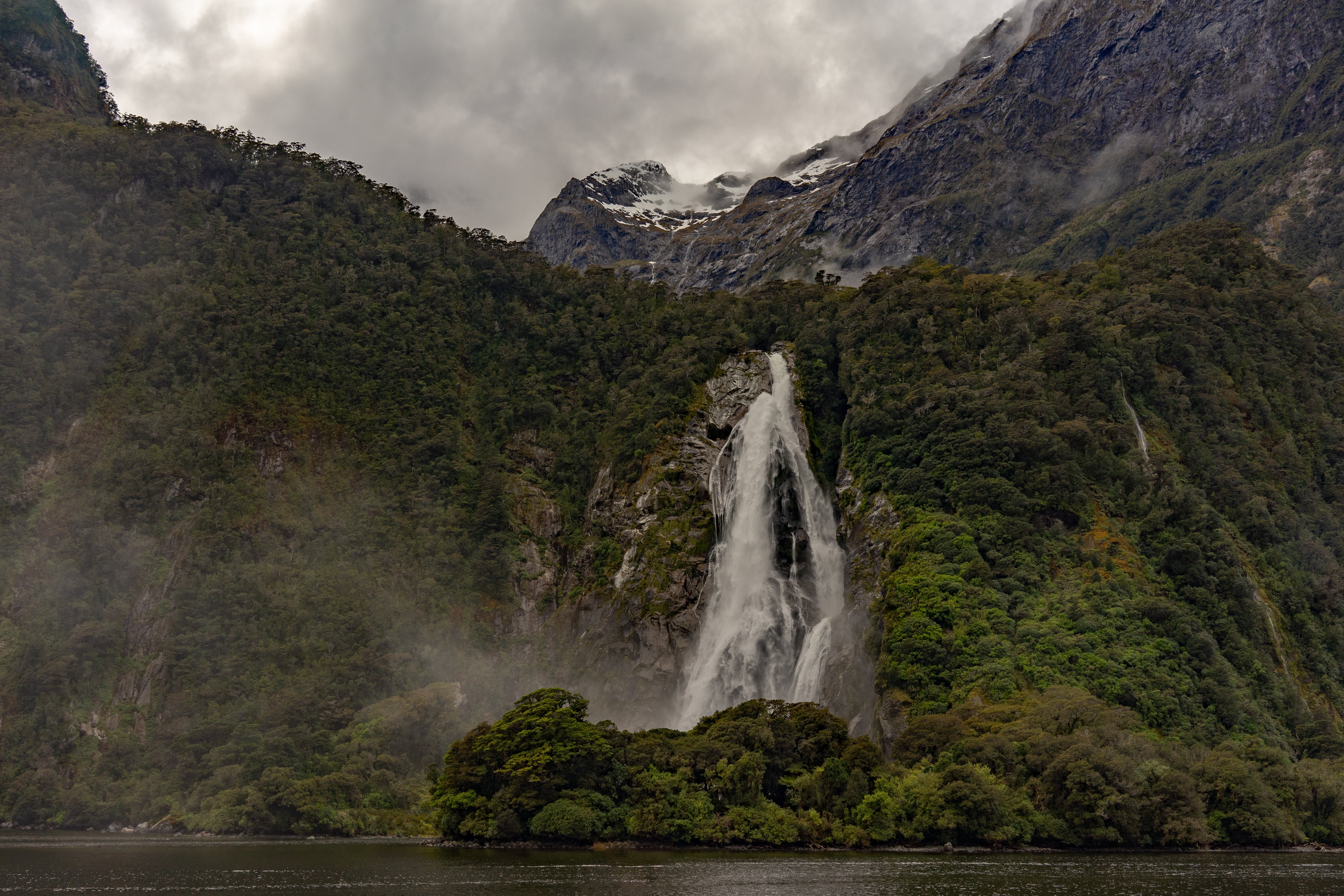 Stunning Waterfall Cascading Through Rocks Beneath Majestic Mountains – Breathtaking Photo