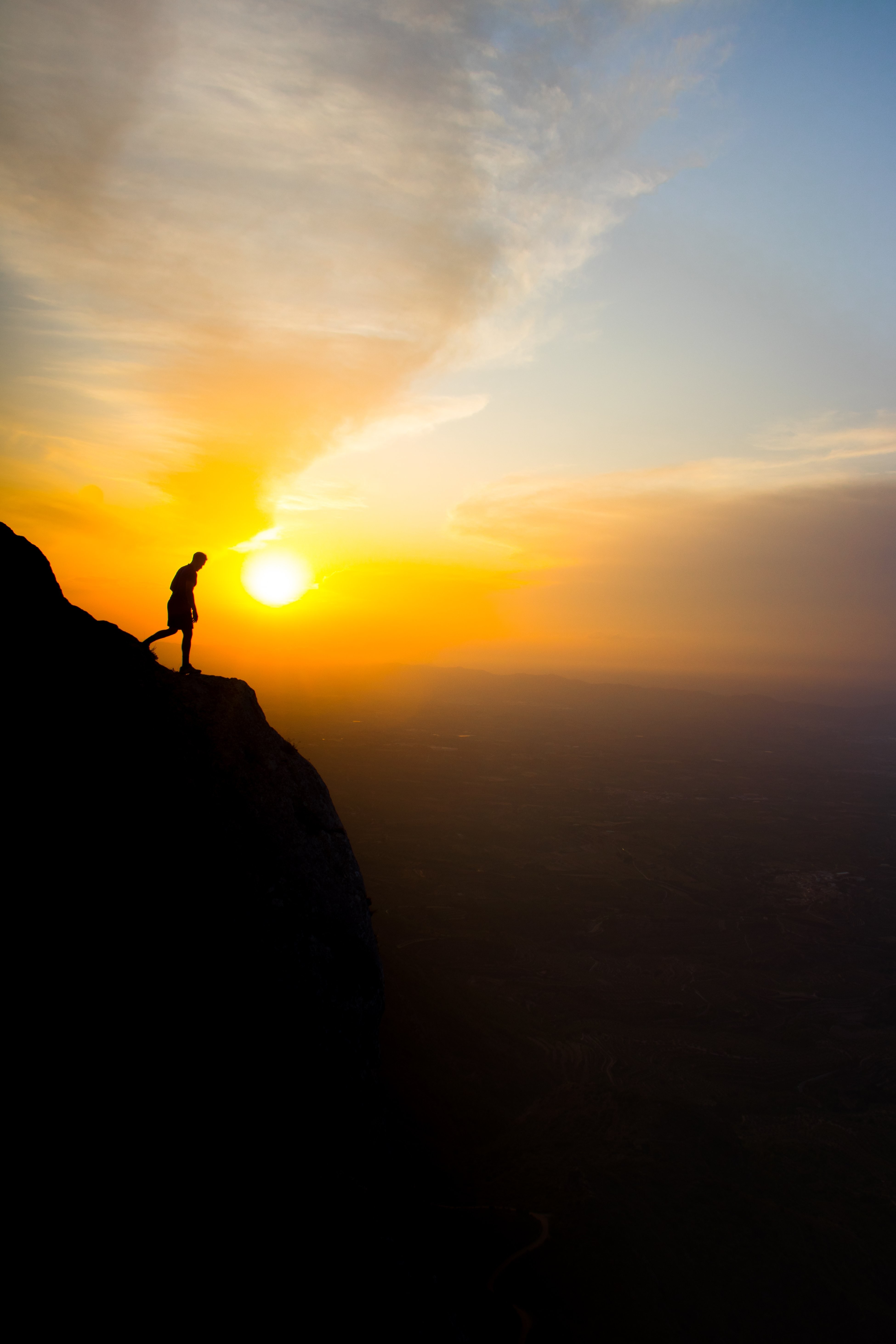 Dramatic Sunset Silhouette: Lone Figure on Cliff Edge – Stunning Photo