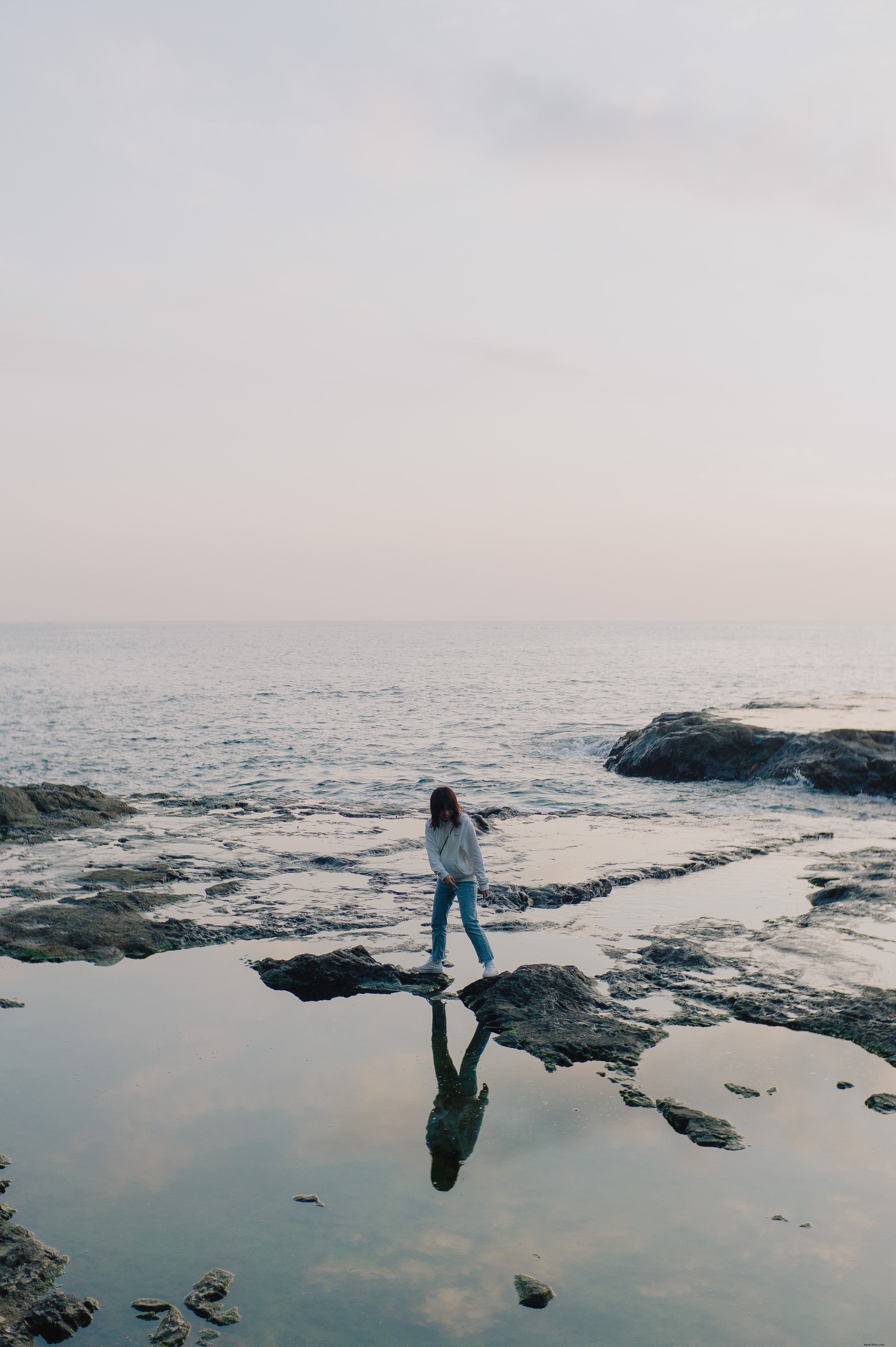 Stunning Photo: Person Boldly Standing on Ocean Shoreline Rocks