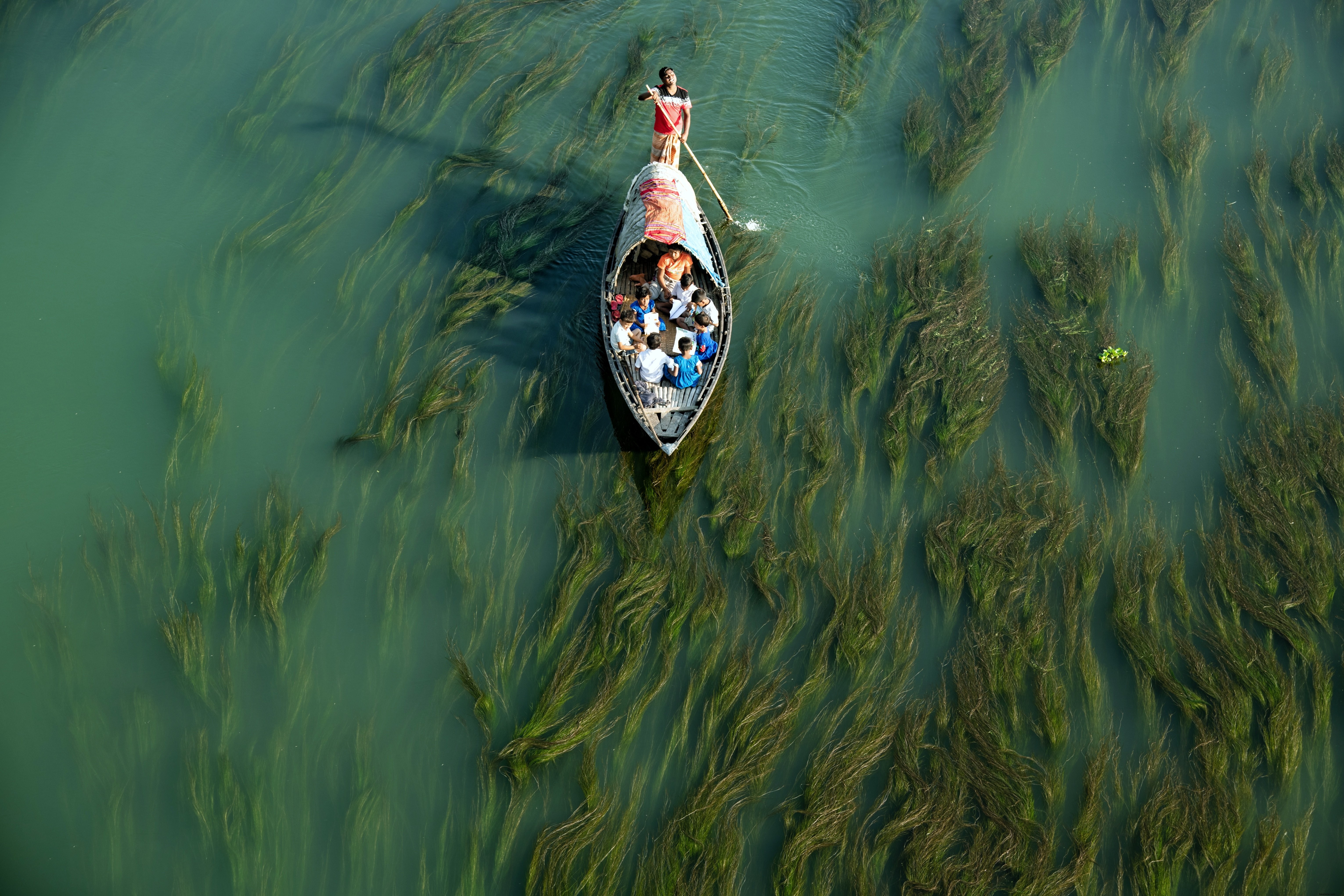 Captivating Photo: Man Pushing Small Boat Through Shallow Waters