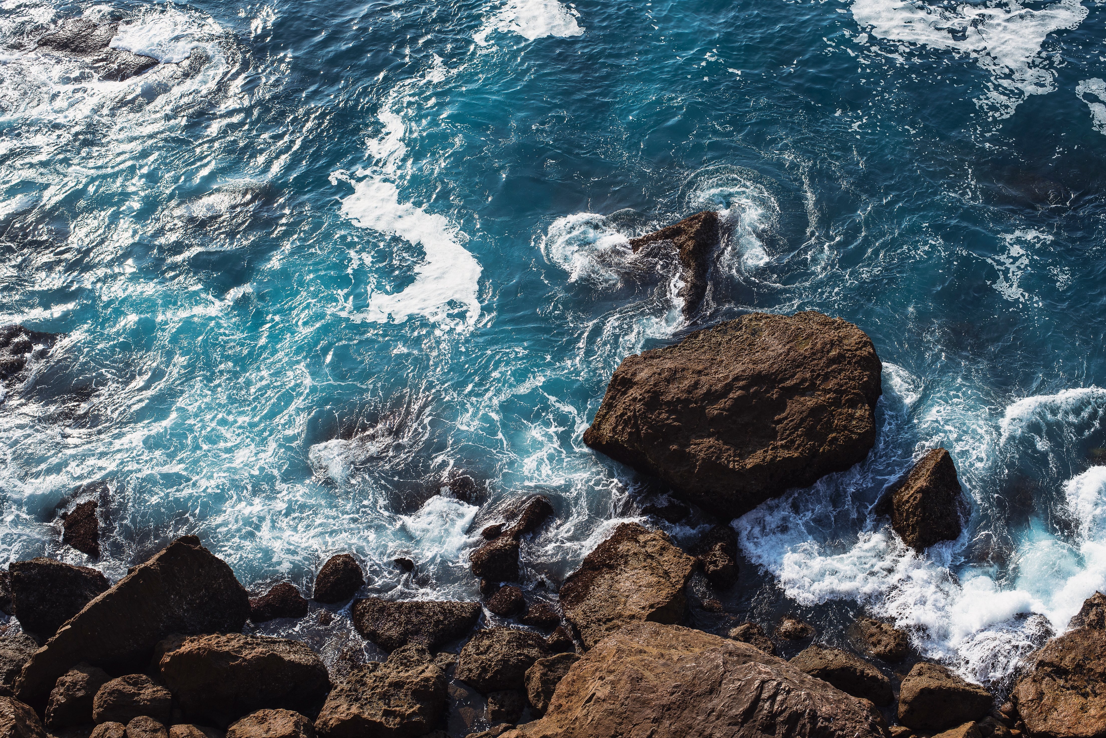 Stunning Photo: Clear Blue Waves Crashing Against Rugged Rocks