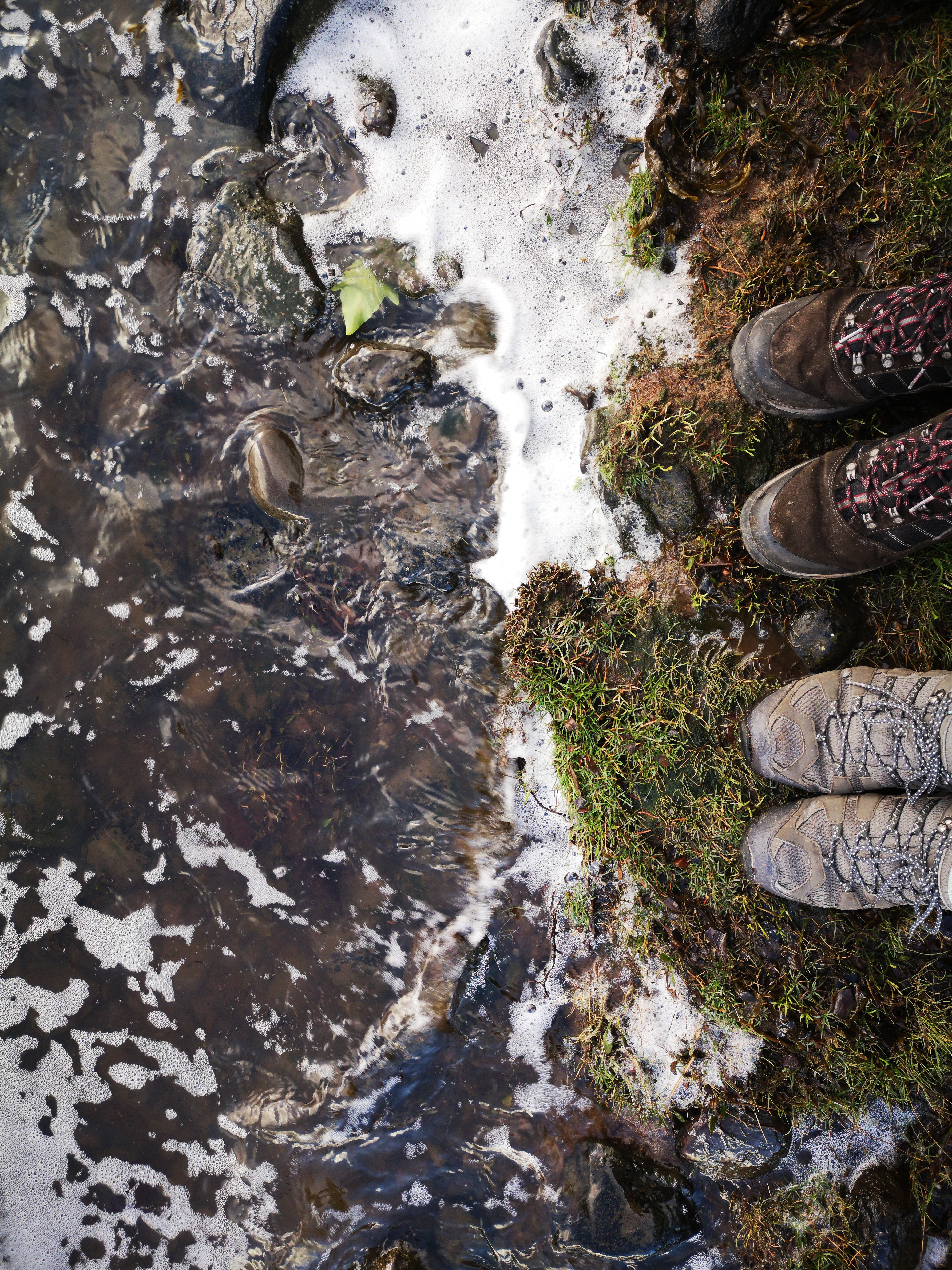 Serene Riverbank: Captivating Photo of Two Pairs of Boots by the Water s Edge