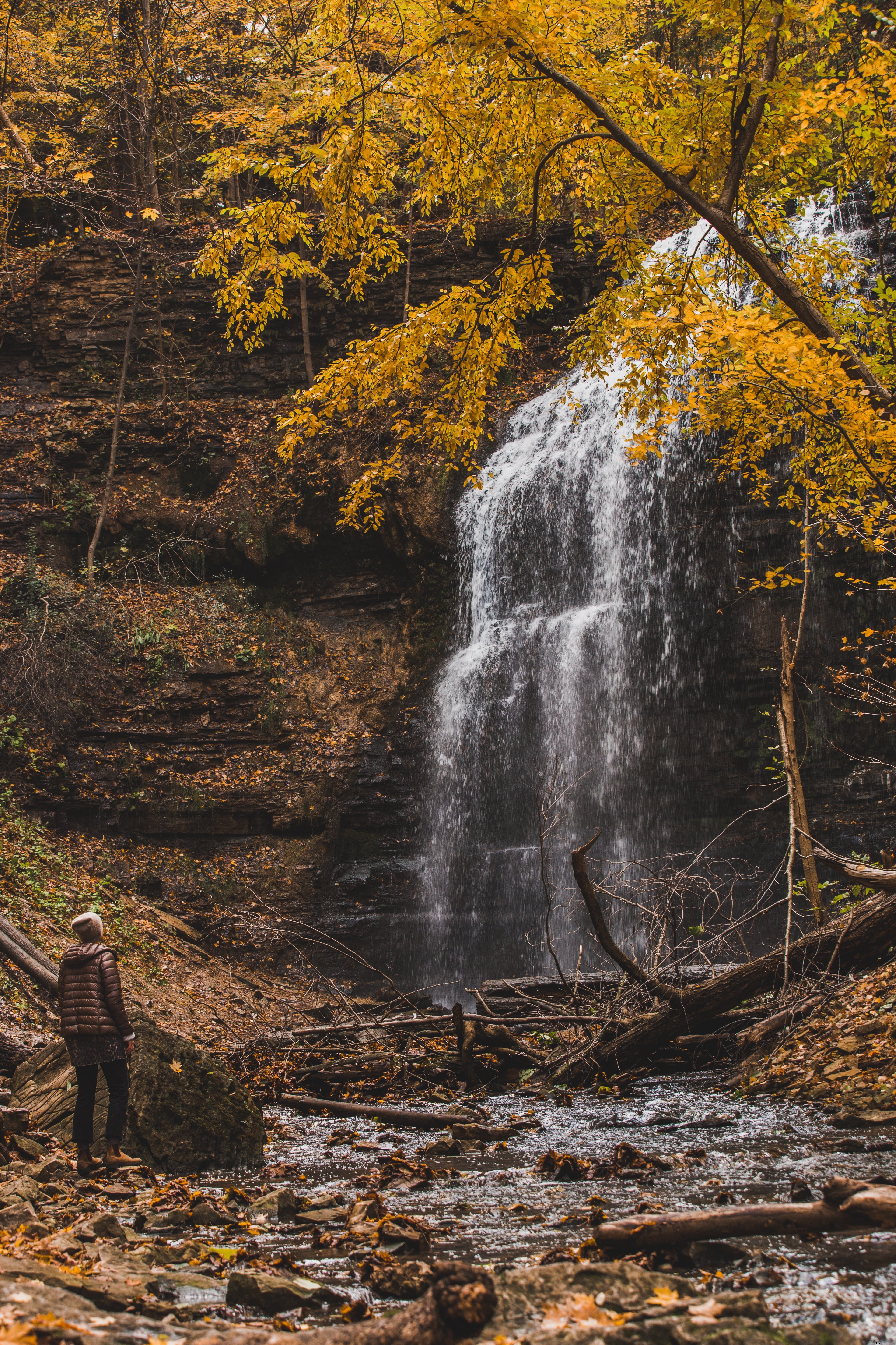 Breathtaking Autumn Photo: Hiker Gazes at Majestic Waterfall