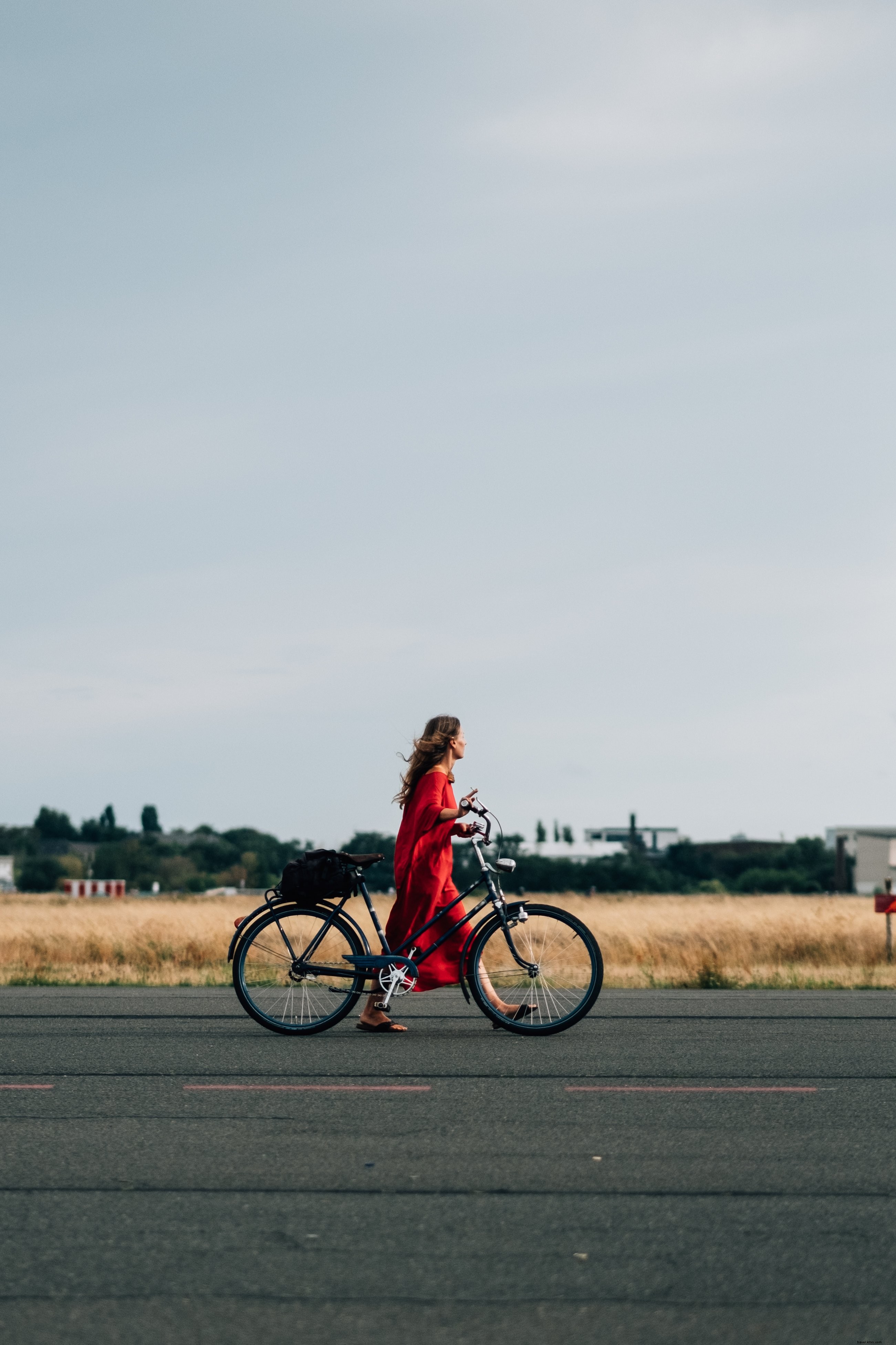 Elegant Woman in Red Dress Strolling with Bicycle on Scenic Road – Stunning Photo