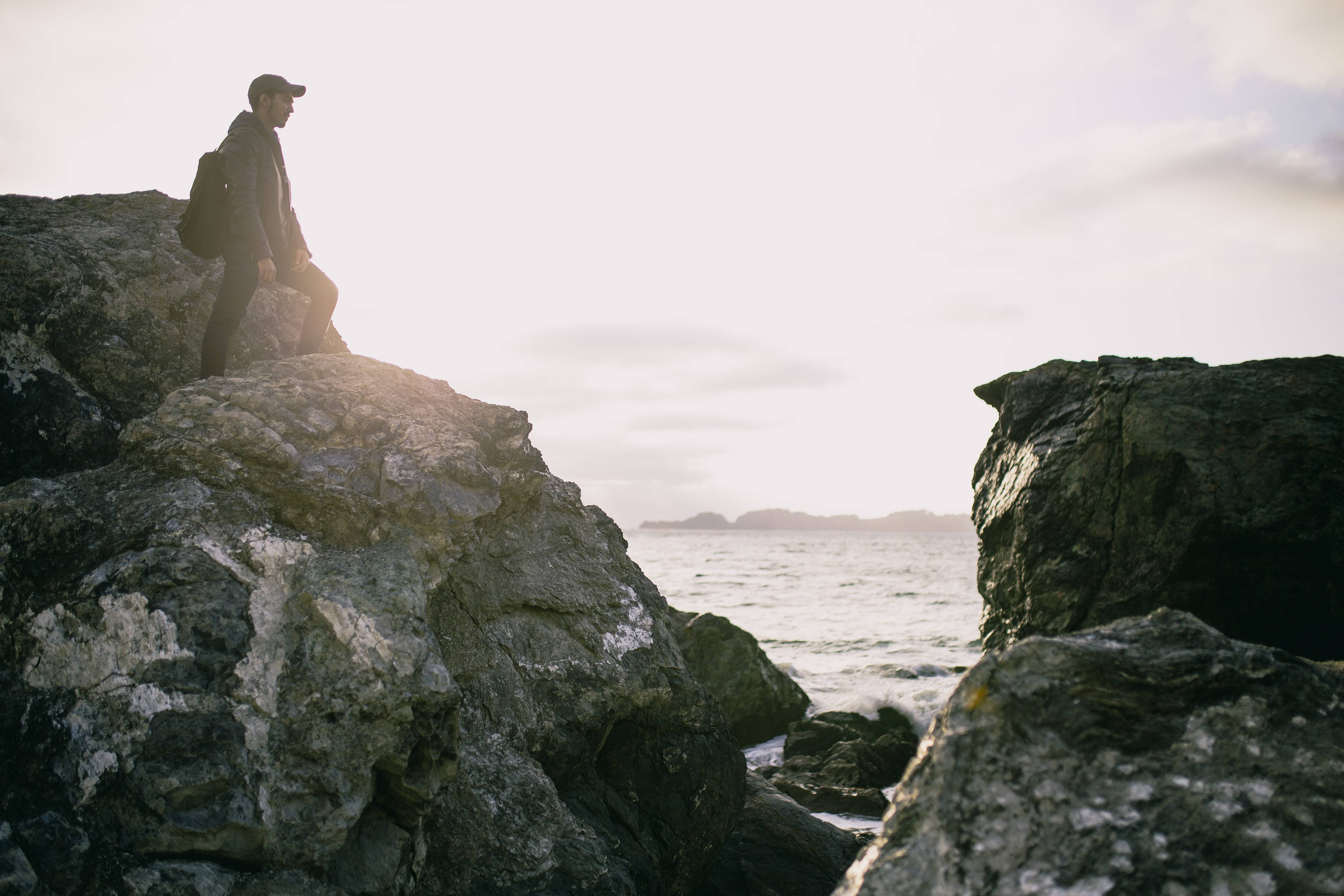 Stunning Photo: Hiker Perched on Towering Rock Overlooking the Ocean
