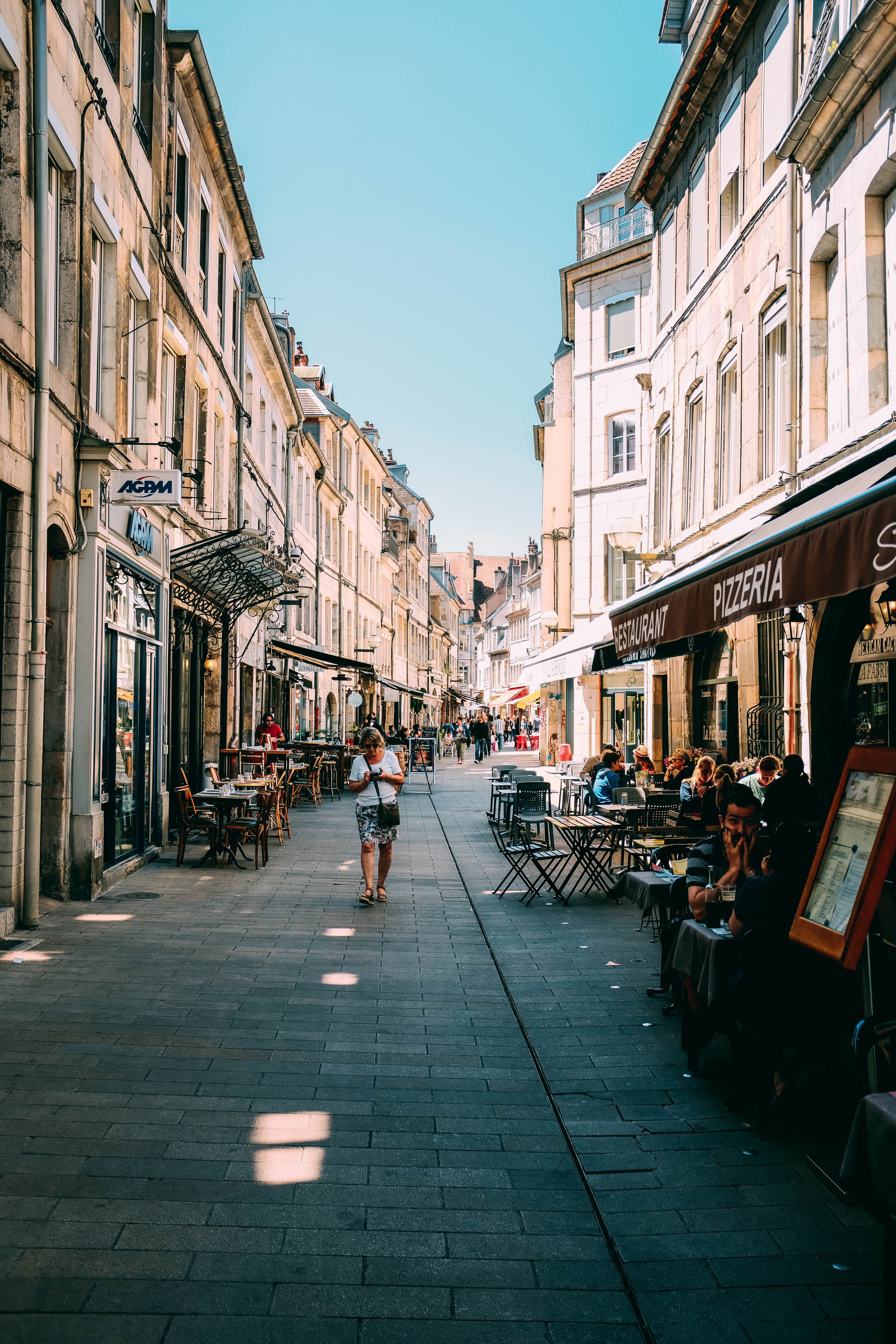 Charming Photo: Tourists Dining Al Fresco at a Pizzeria on a Picturesque European Street