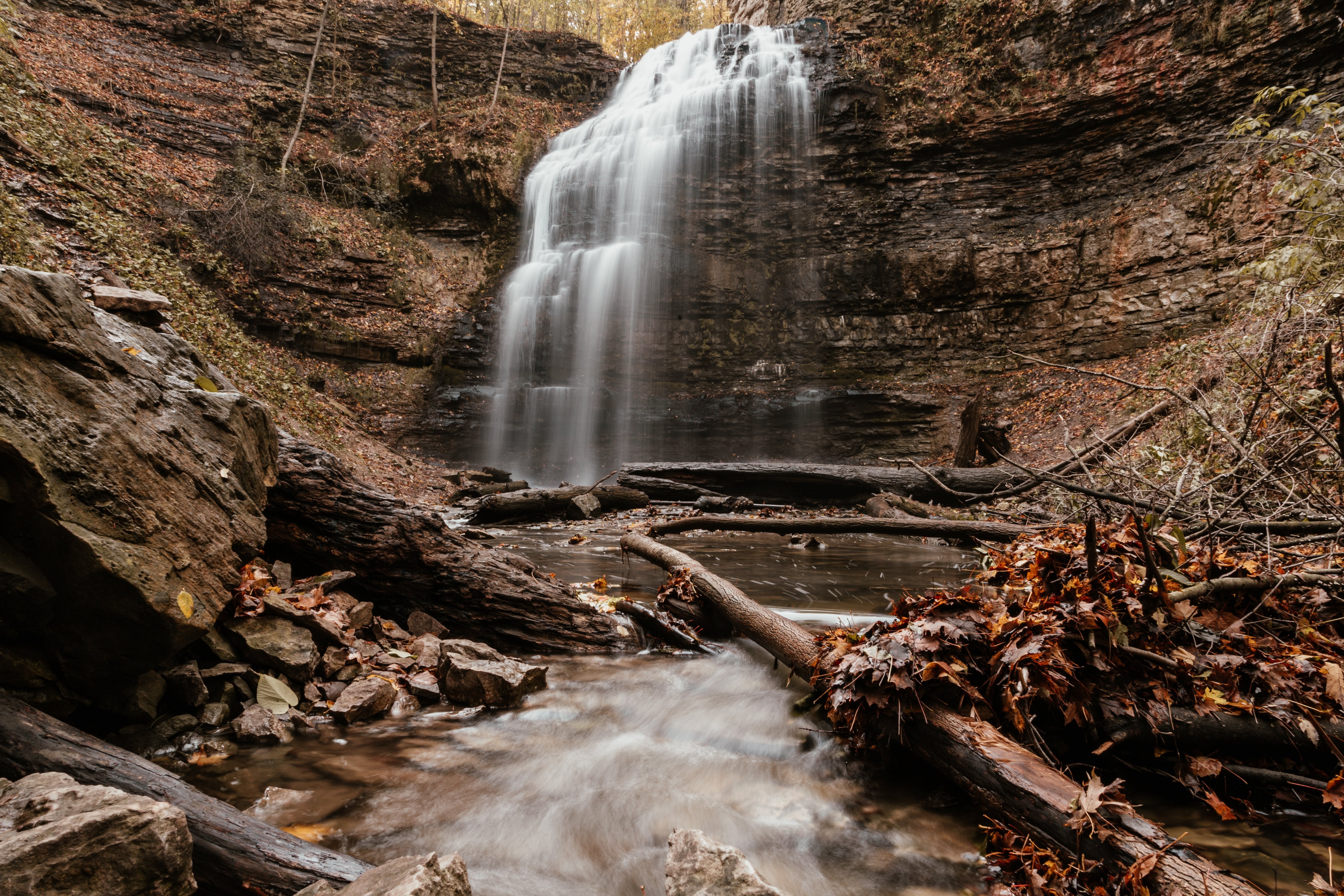 Stunning Waterfall Cascading Over Vibrant Autumn Leaves – Breathtaking Nature Photo