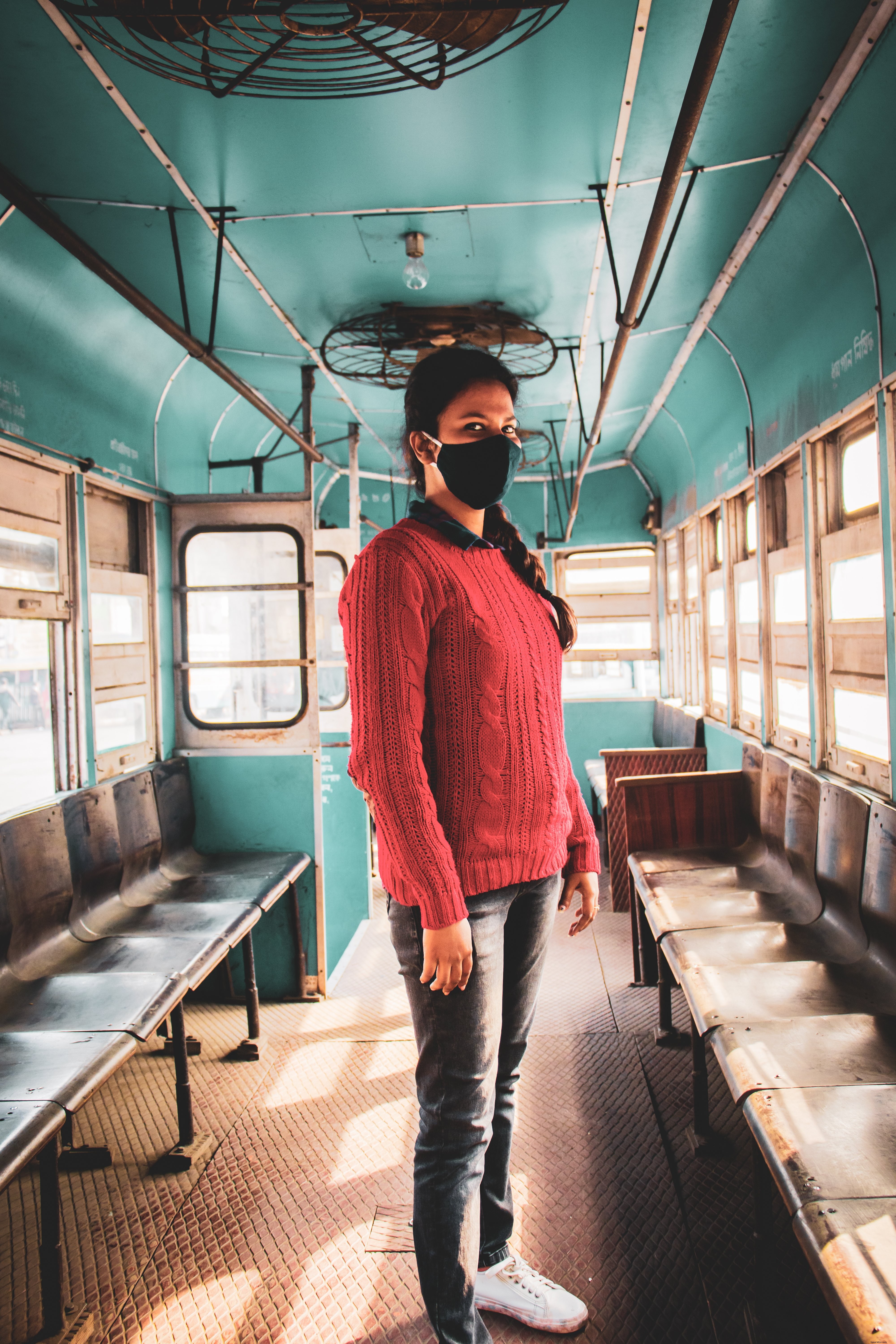 Captivating Photo: Person in Black Face Mask on Vibrant Blue Bus