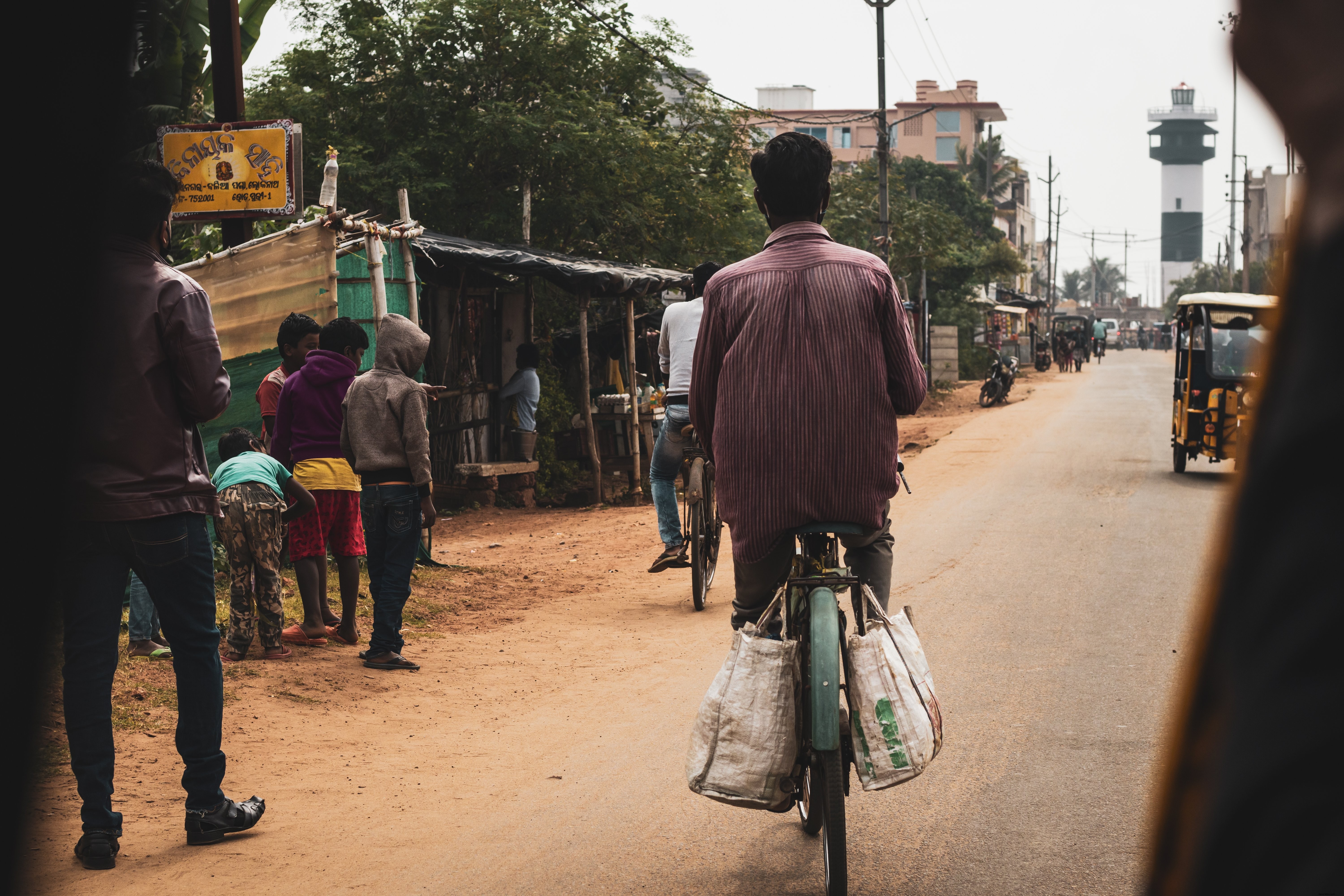 Stunning Photo: Cyclist Riding Down a Dusty Dirt Road in a Rural Town