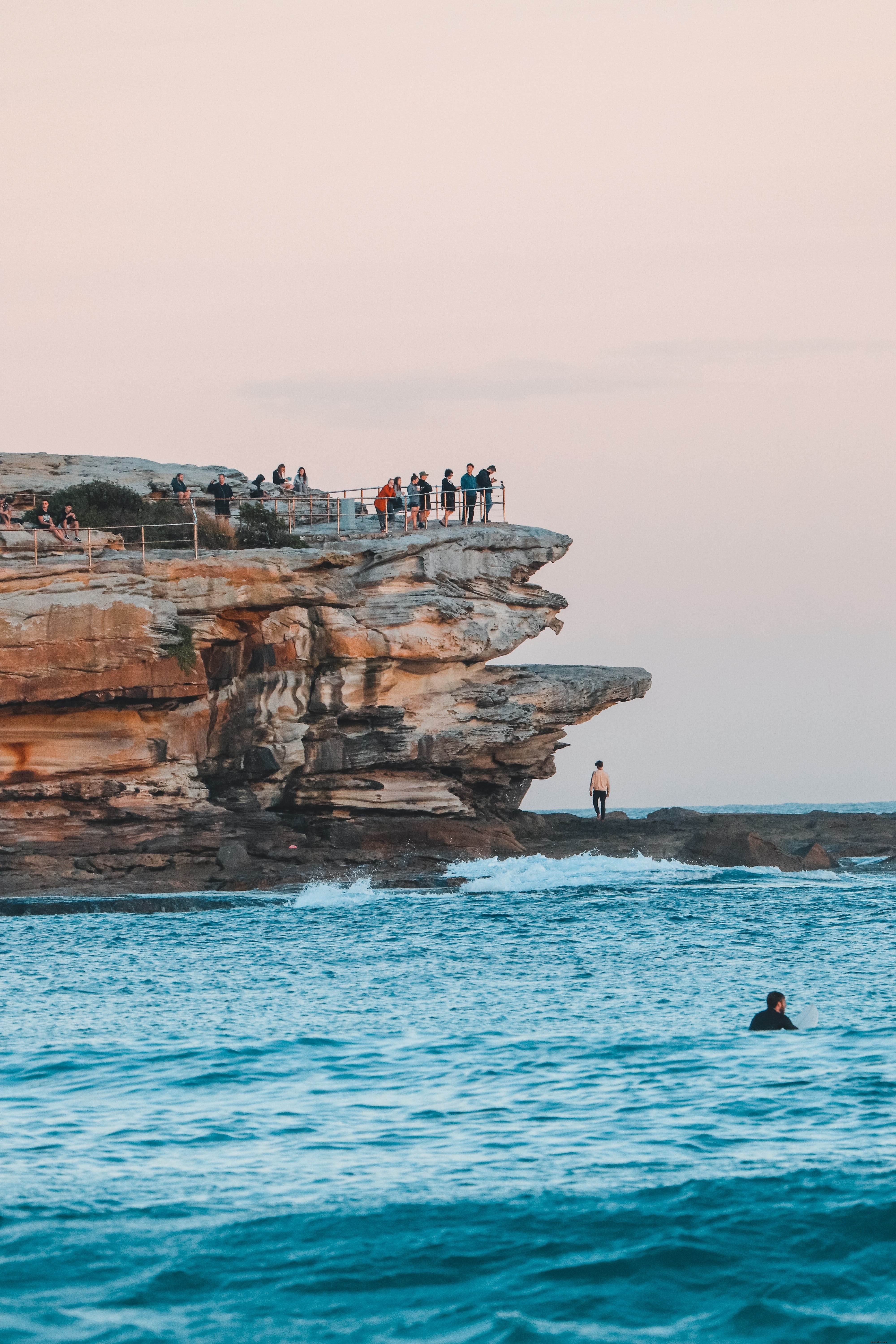 Stunning Cliffside View: People Gazing at the Ocean from Towering Rocks
