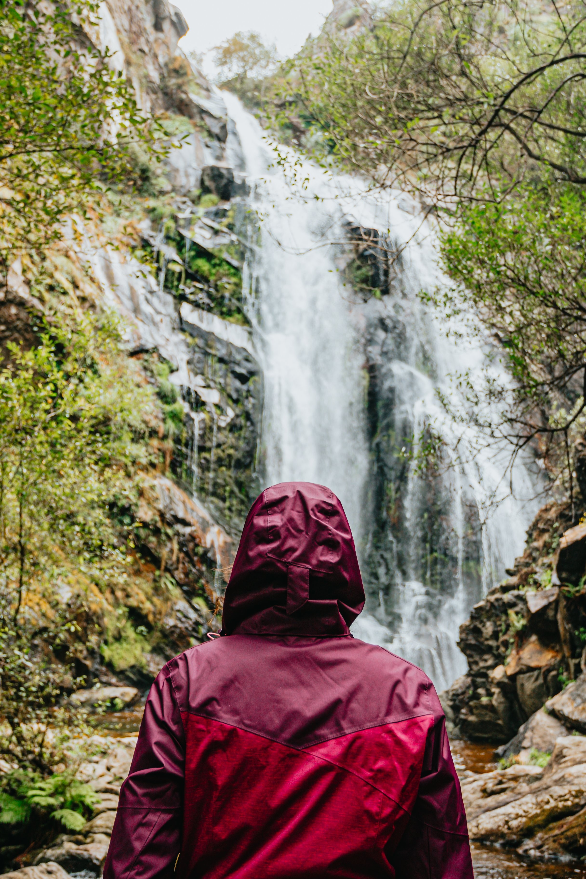 Stunning Photo: Person in Red Raincoat Awestruck by Majestic Waterfall
