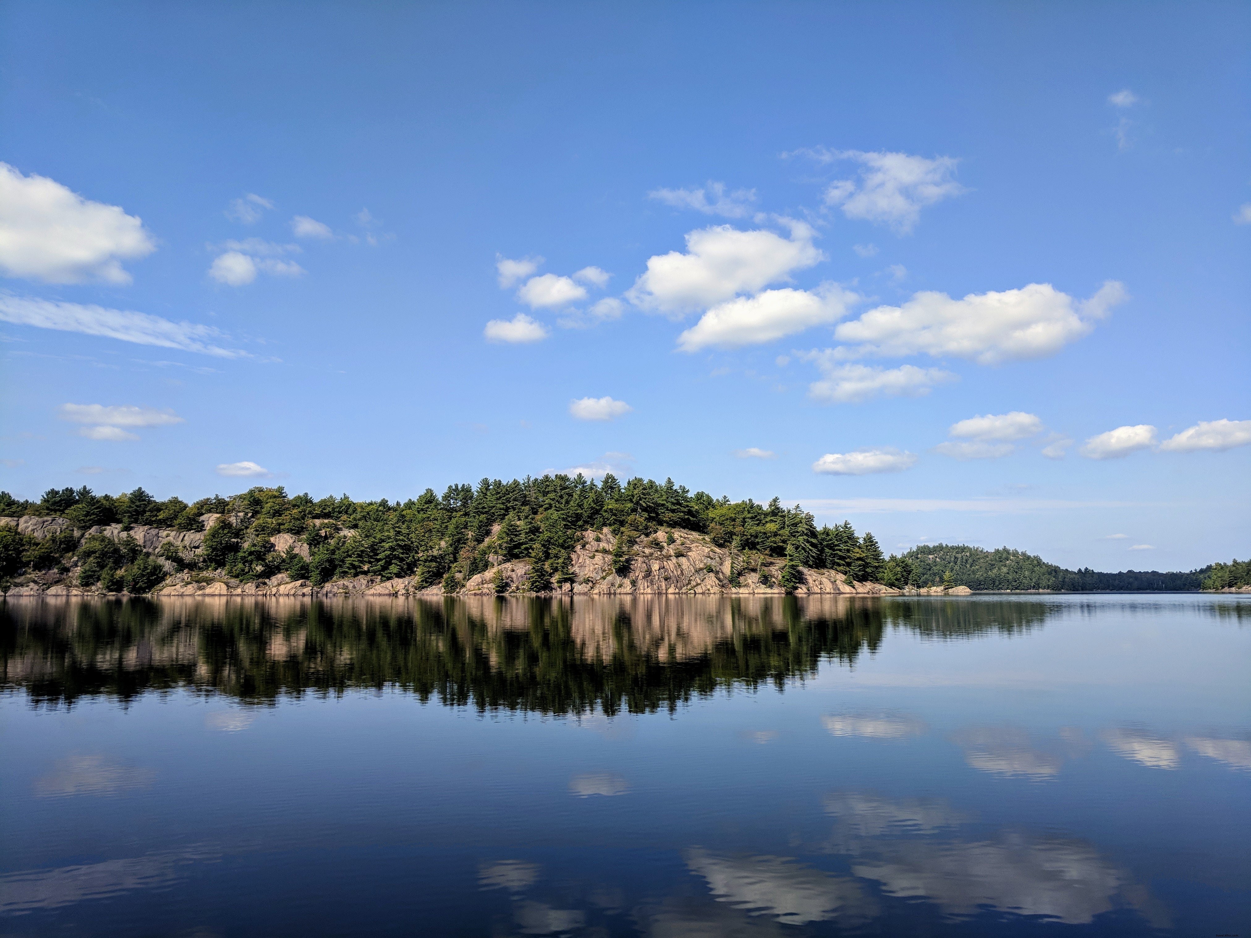 Stunning Reflections of Rocks and Trees on a Serene Lake – Captivating Nature Photo