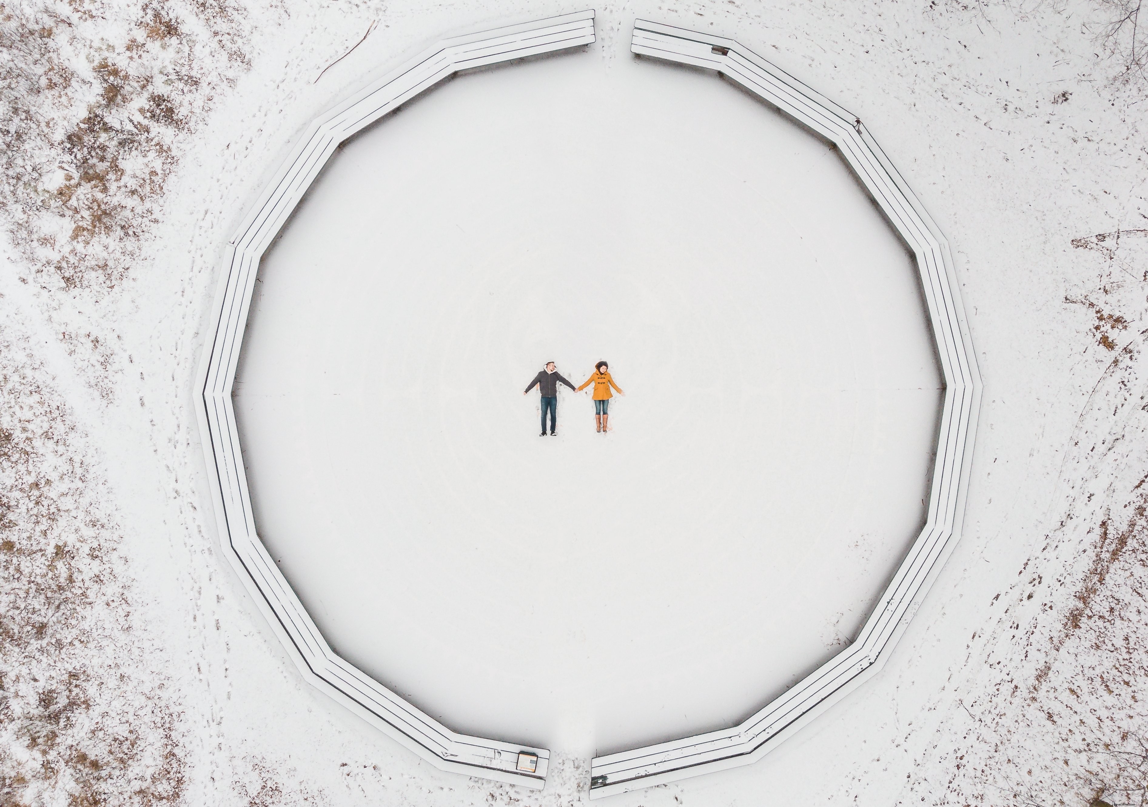 Breathtaking Aerial View: Couple Making Snow Angels in Winter Wonderland