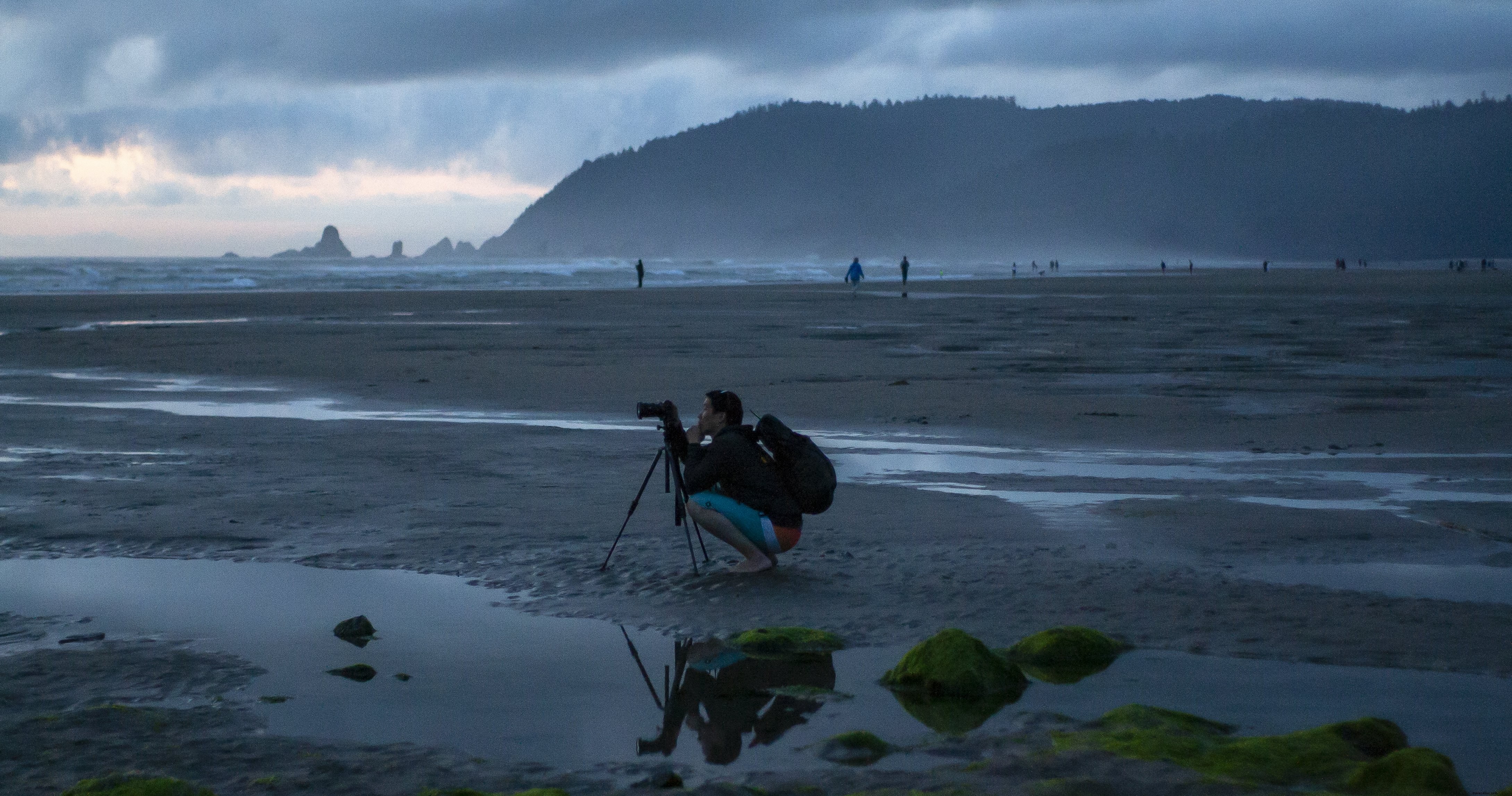 Stunning Misty Beach Scene: Photographer Crouches at Tripod for Perfect Shot