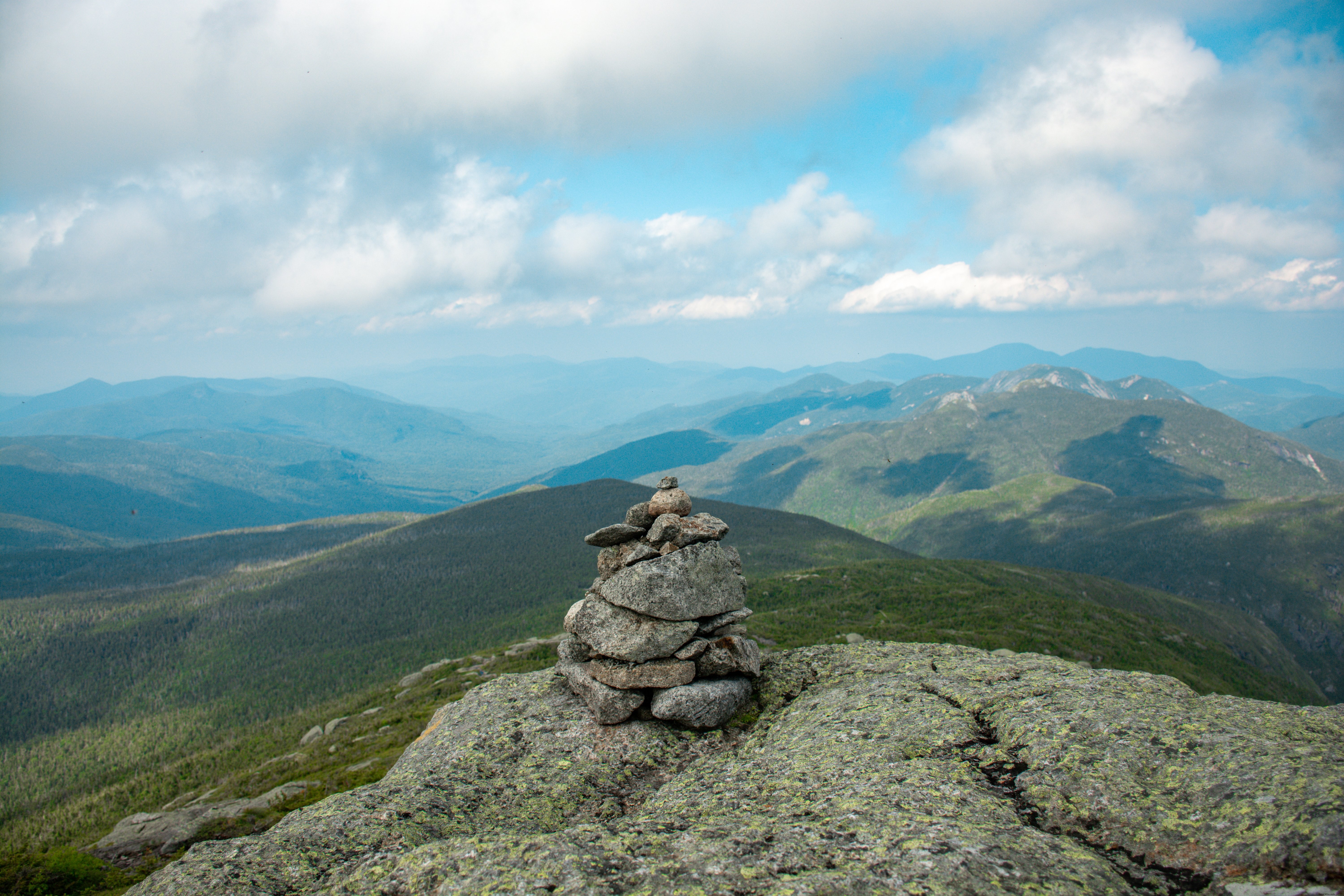 Stunning Photo: Small Pebble Cairn Atop a Majestic Mountain Peak