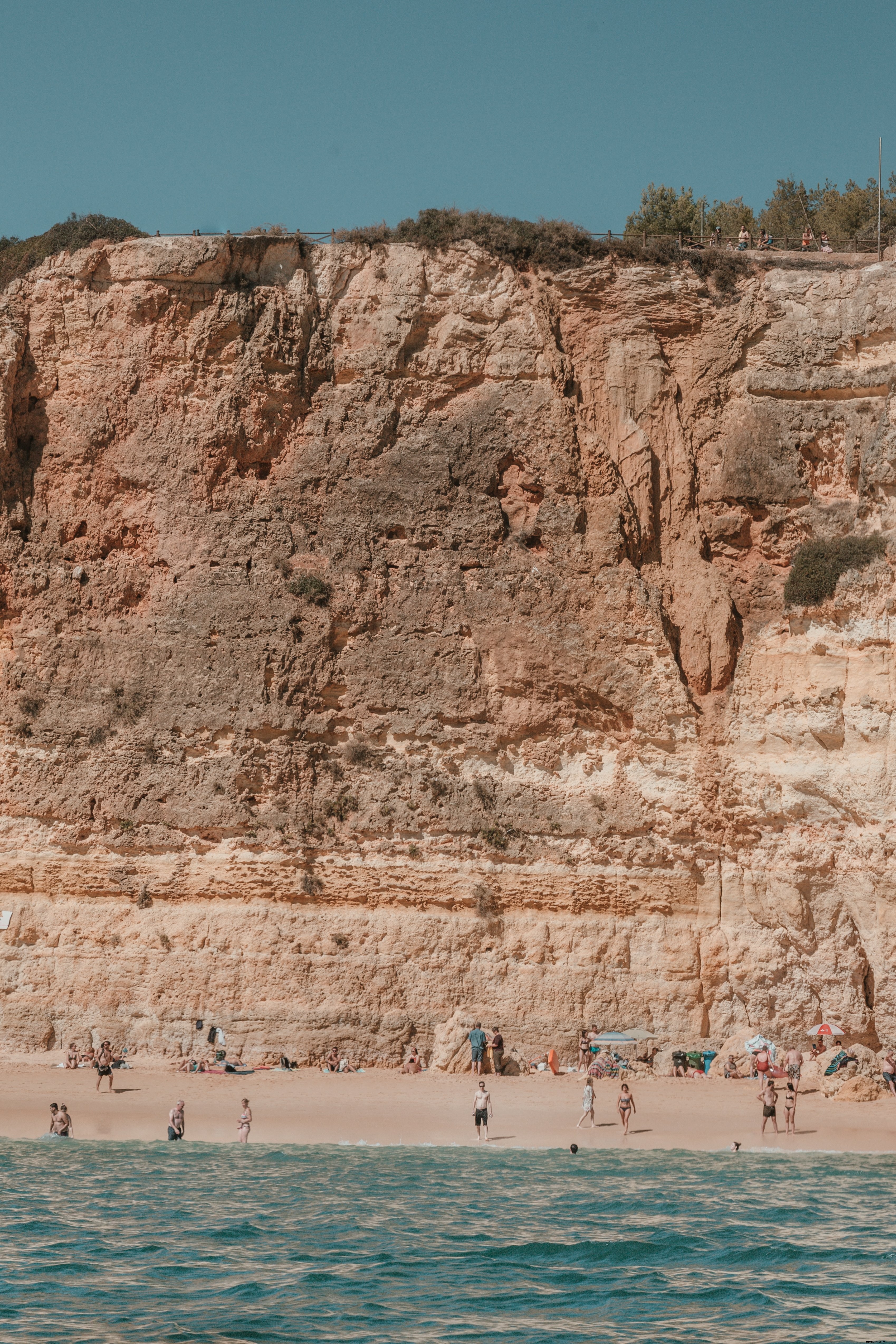 Stunning Sun-Cracked Cliffs Overlook Bathers on Pristine Sandy Beach Photo