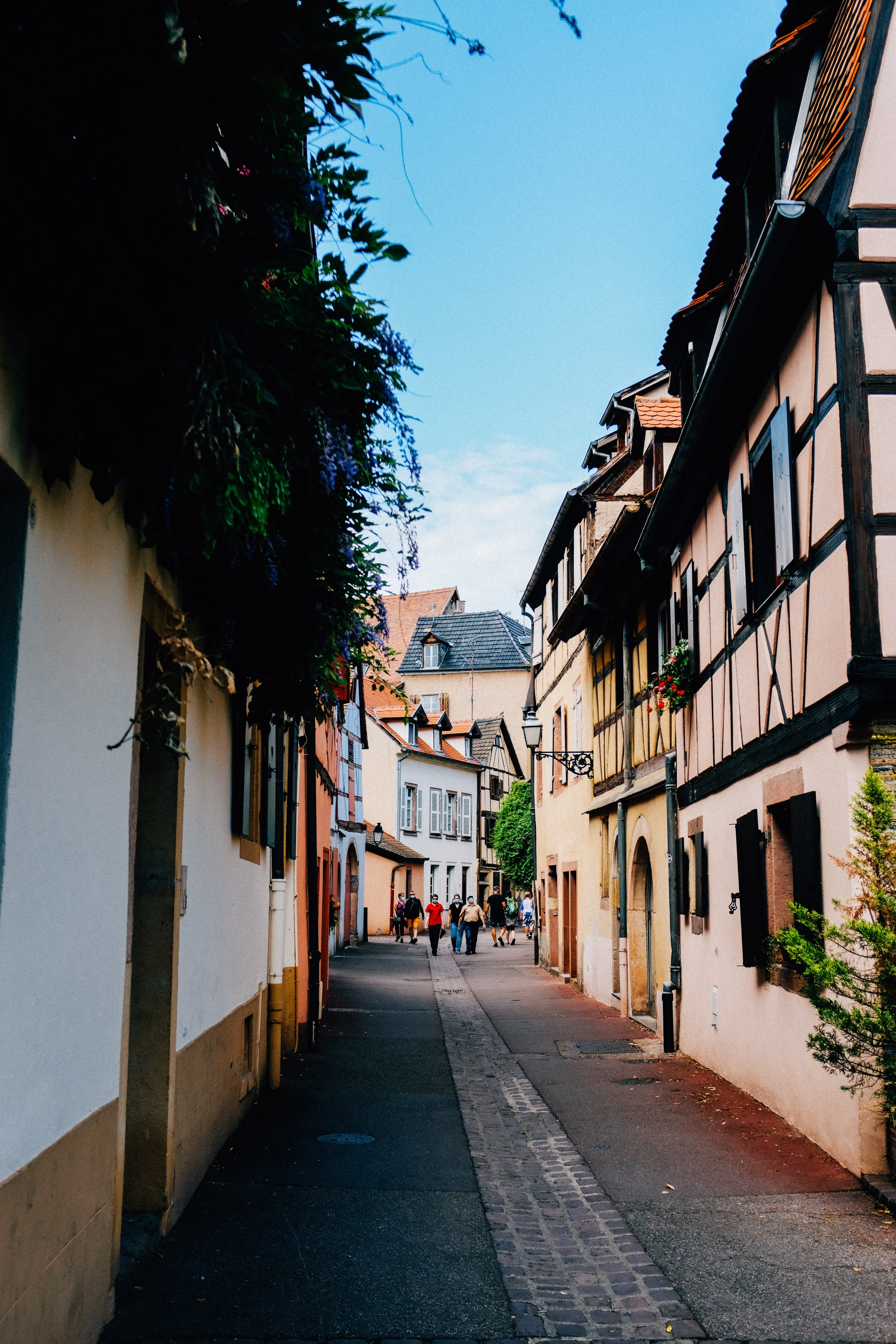 Vibrant Summer Stroll: People Walking on Picturesque Cobbled Street Photo