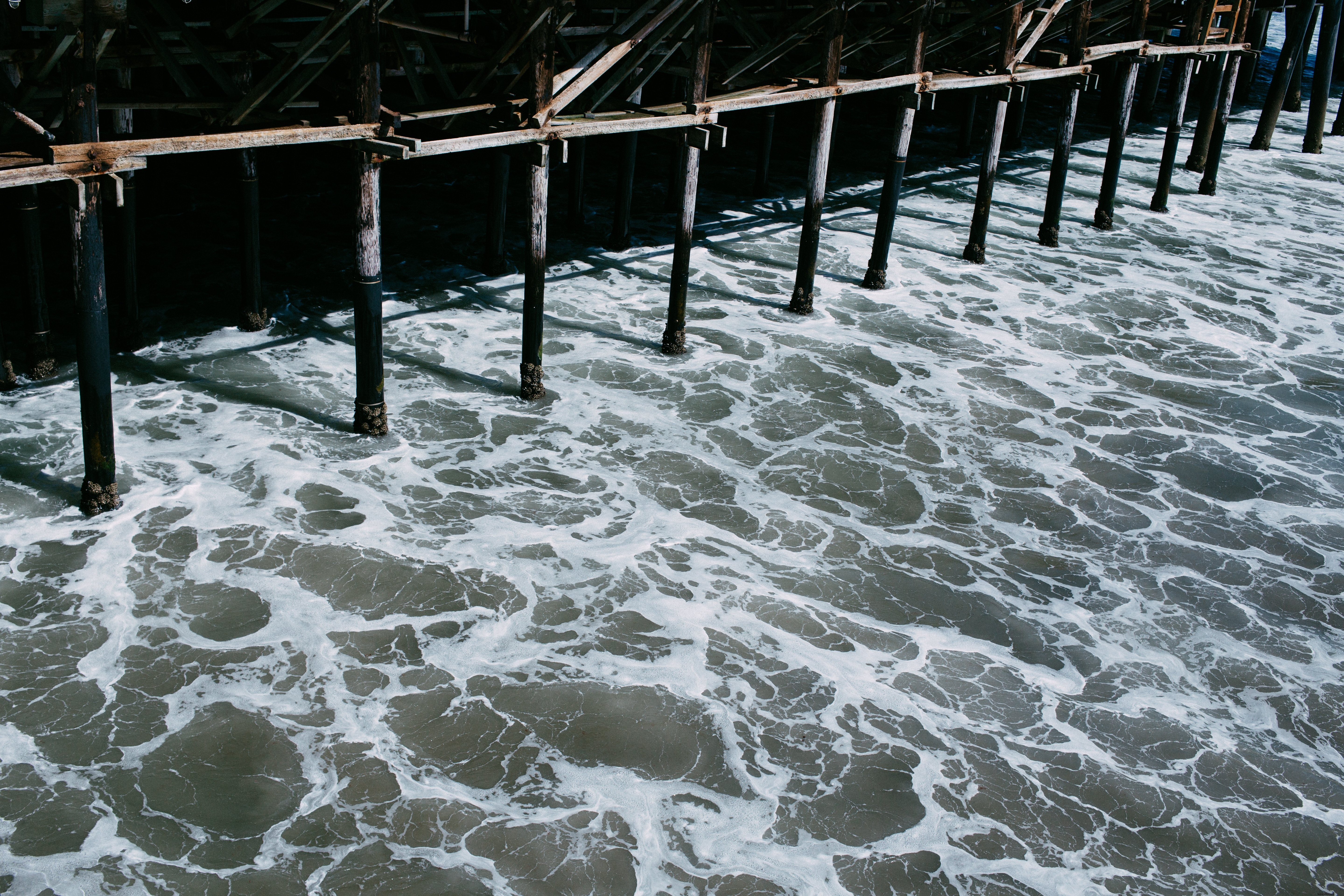 Captivating Photo: Water Flowing Beneath a Shadowy Pier