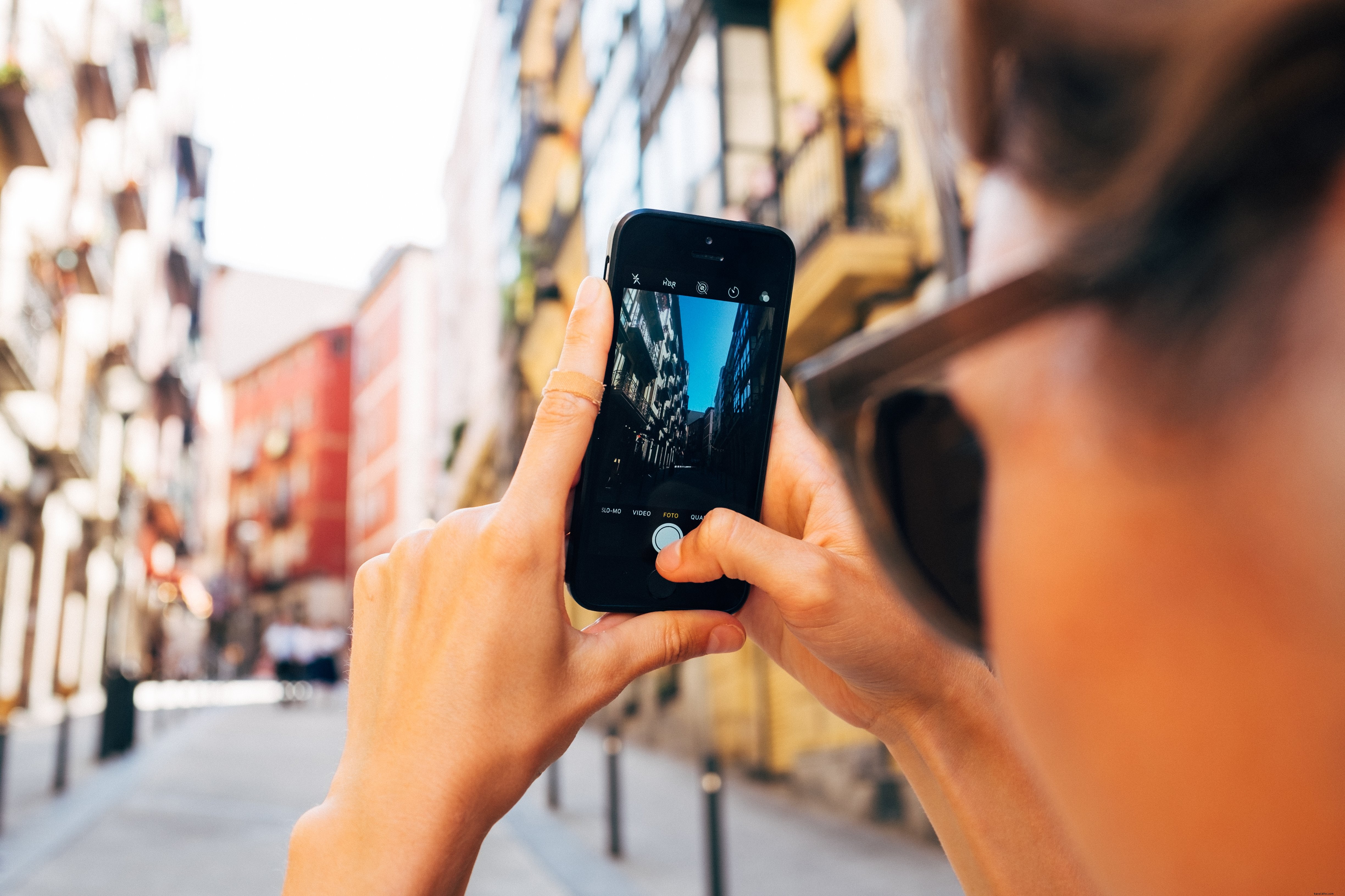 Woman Capturing Sunny Street Scene on Her Smartphone