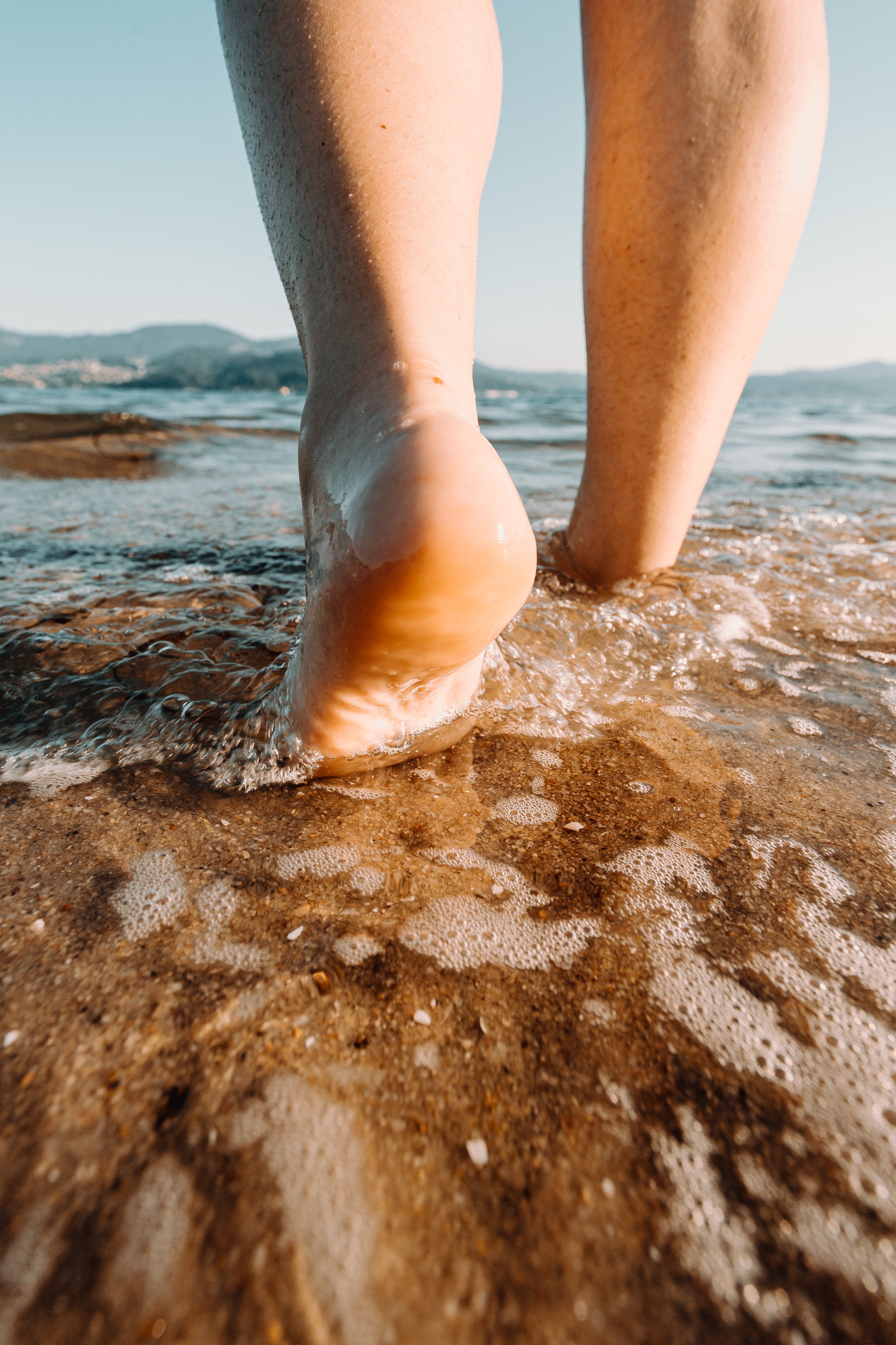 Bare Feet Stepping into Crystal Clear Water: Serene Beach Photo