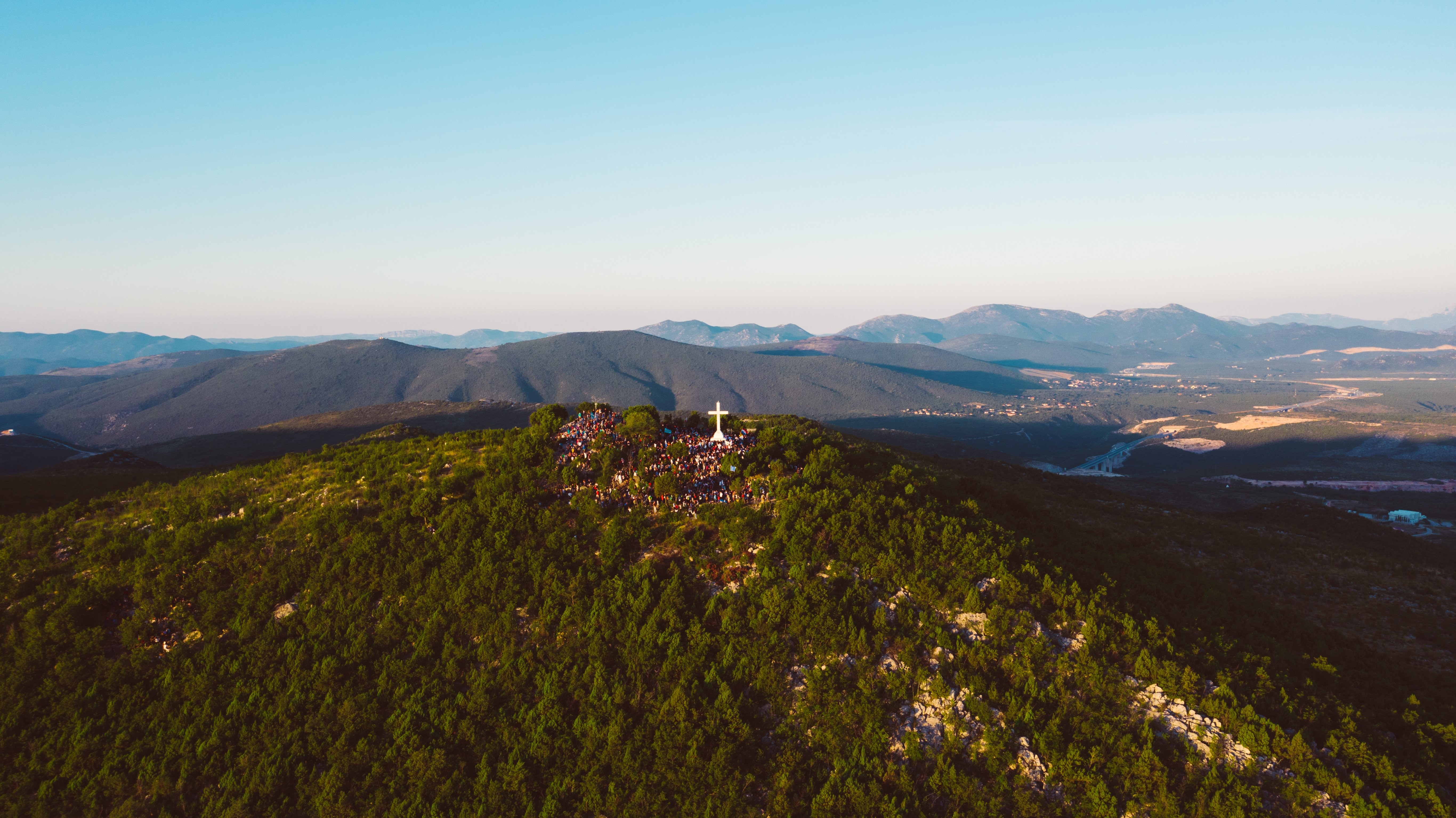 Breathtaking Photo: Tourists Admire Giant Cross atop Mountain Summit