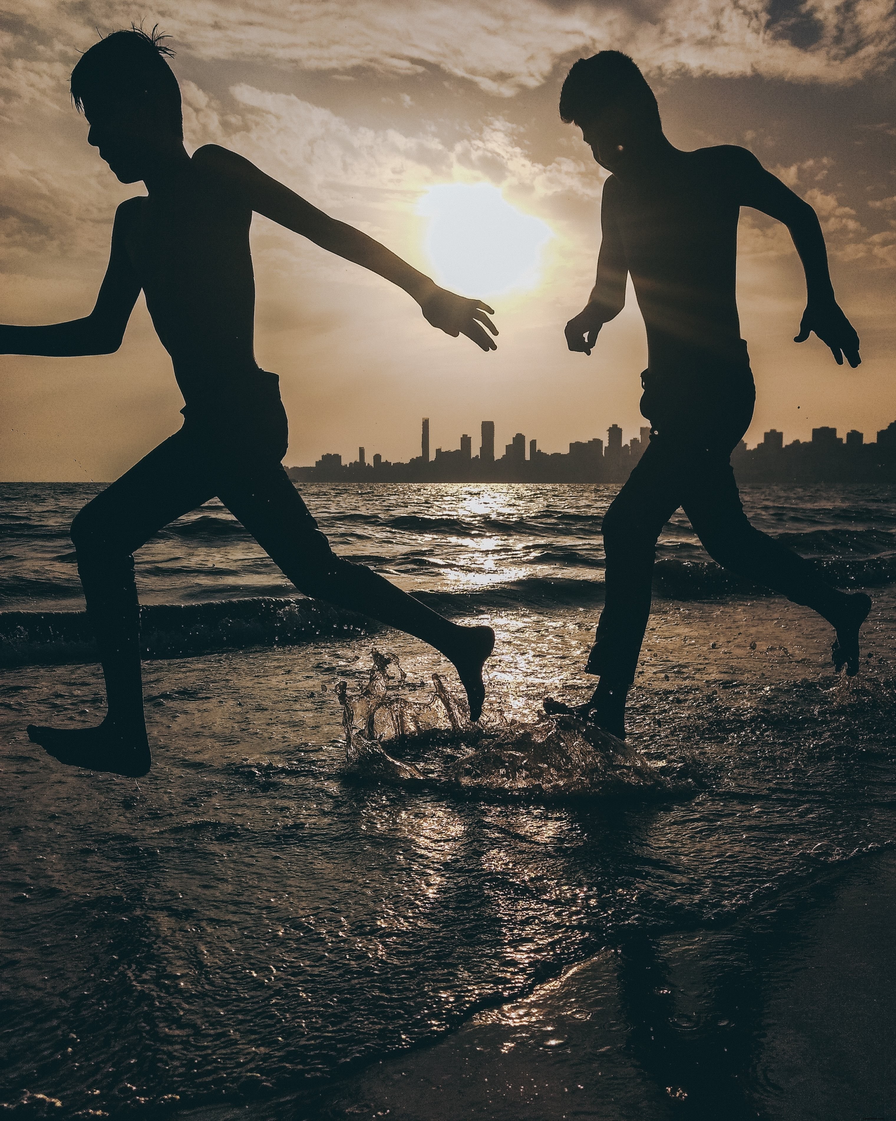 Captivating Beach Silhouettes: Two People Joyfully Splashing in Waves