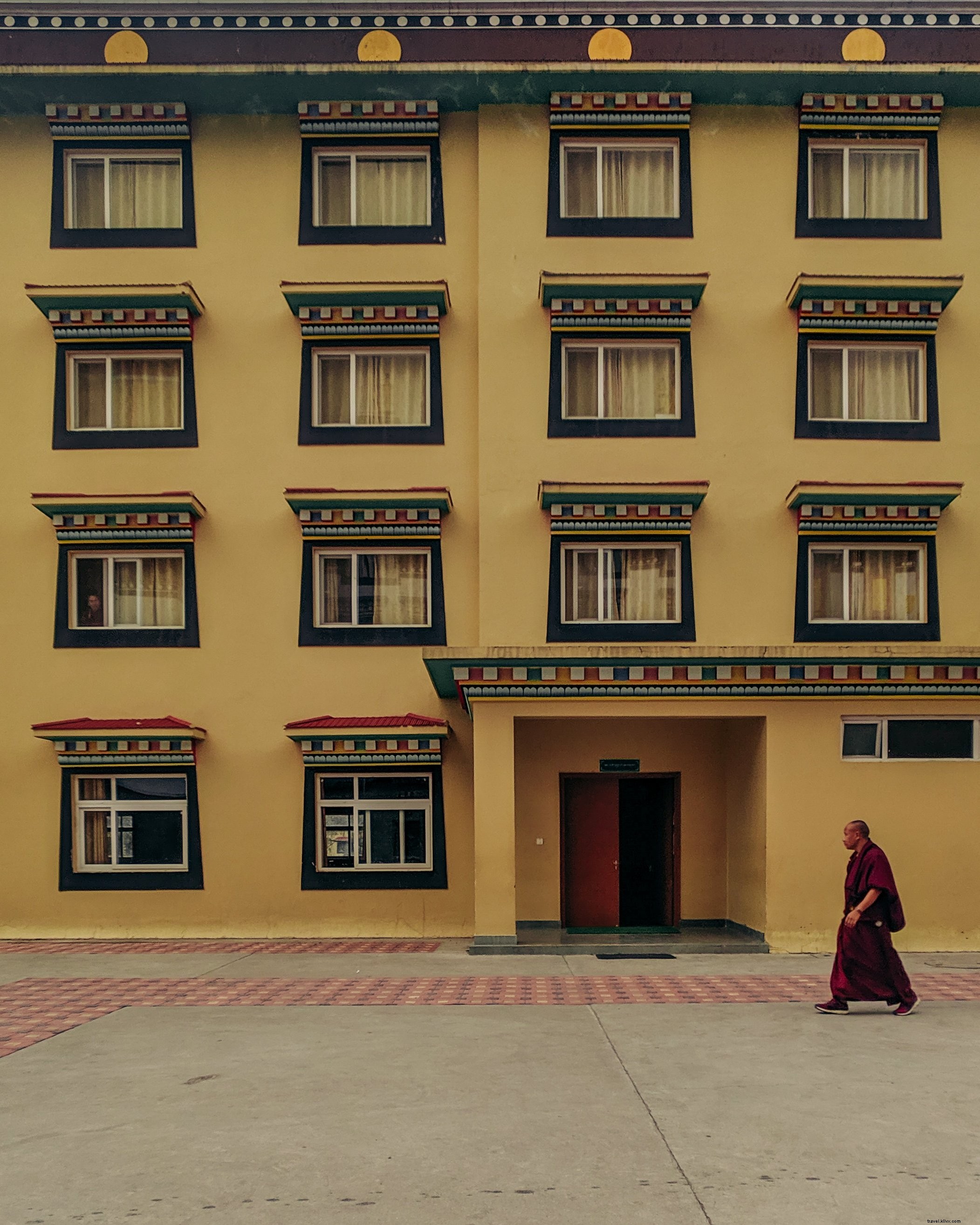 Serene Photo: Buddhist Monk Walking Past Vibrant Yellow Building