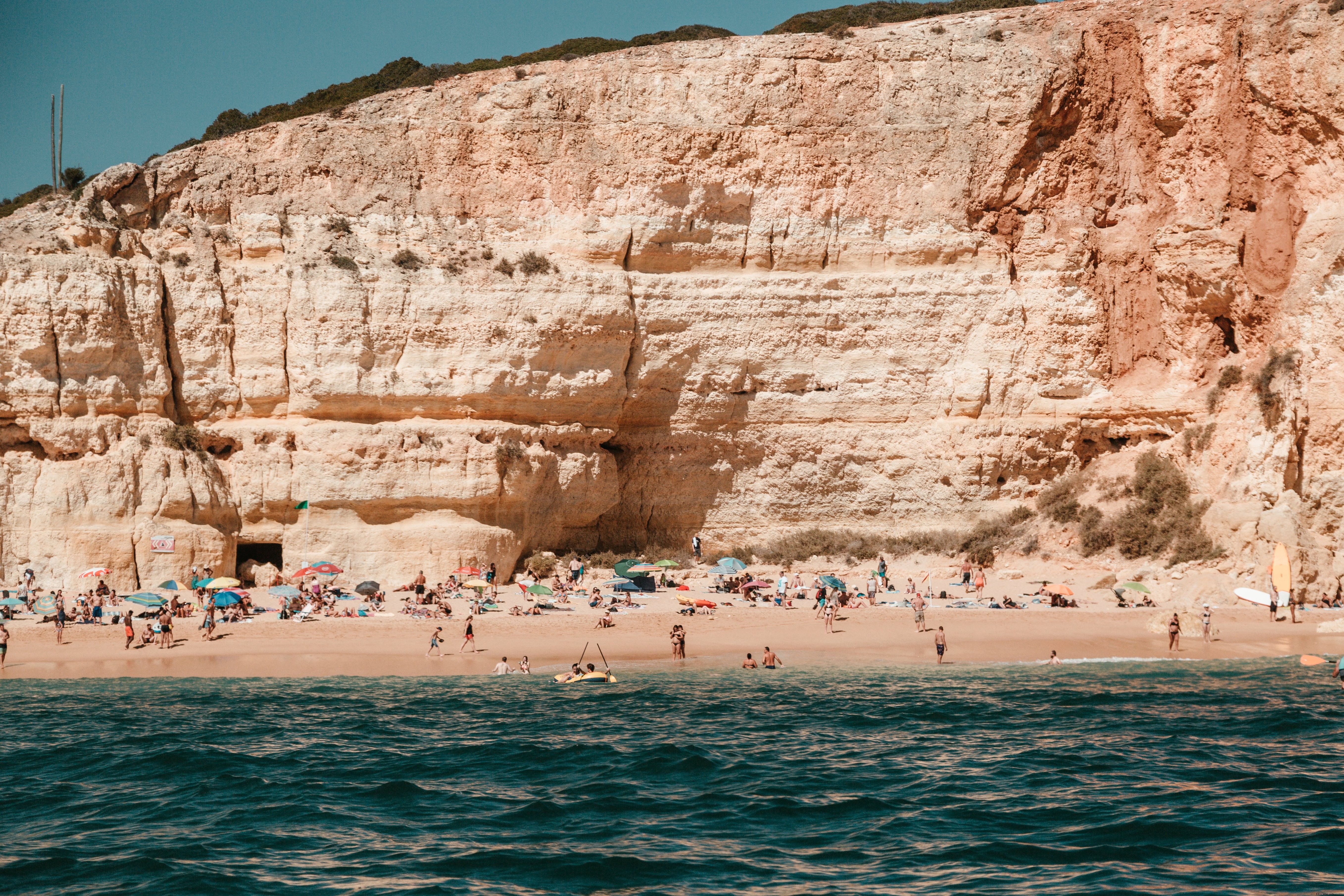 Stunning Photo: Bathers on Sandy Beach Against Dramatic Craggy Cliffs