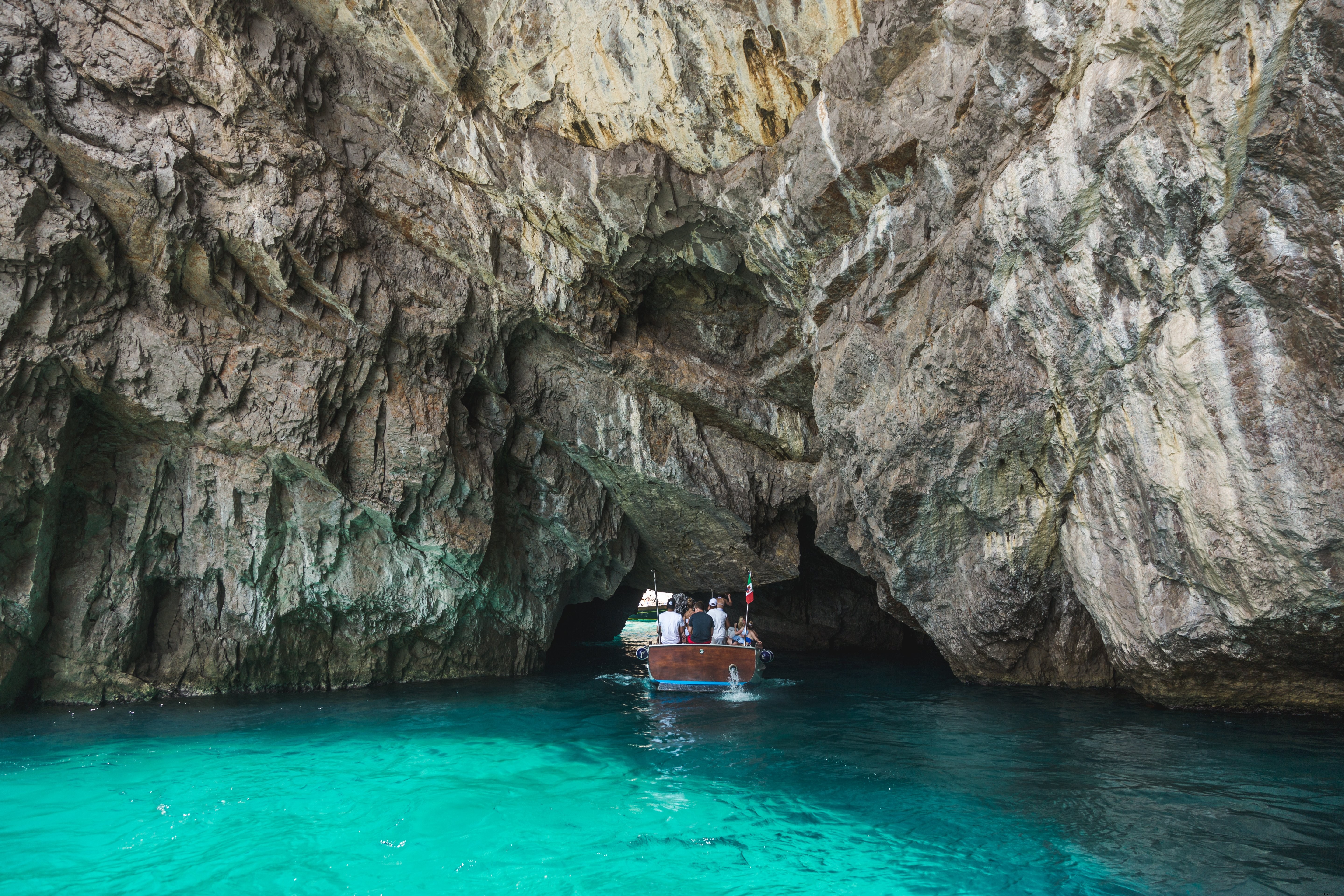 Stunning Photo: Small Boat Sailing Beneath Towering Rocks