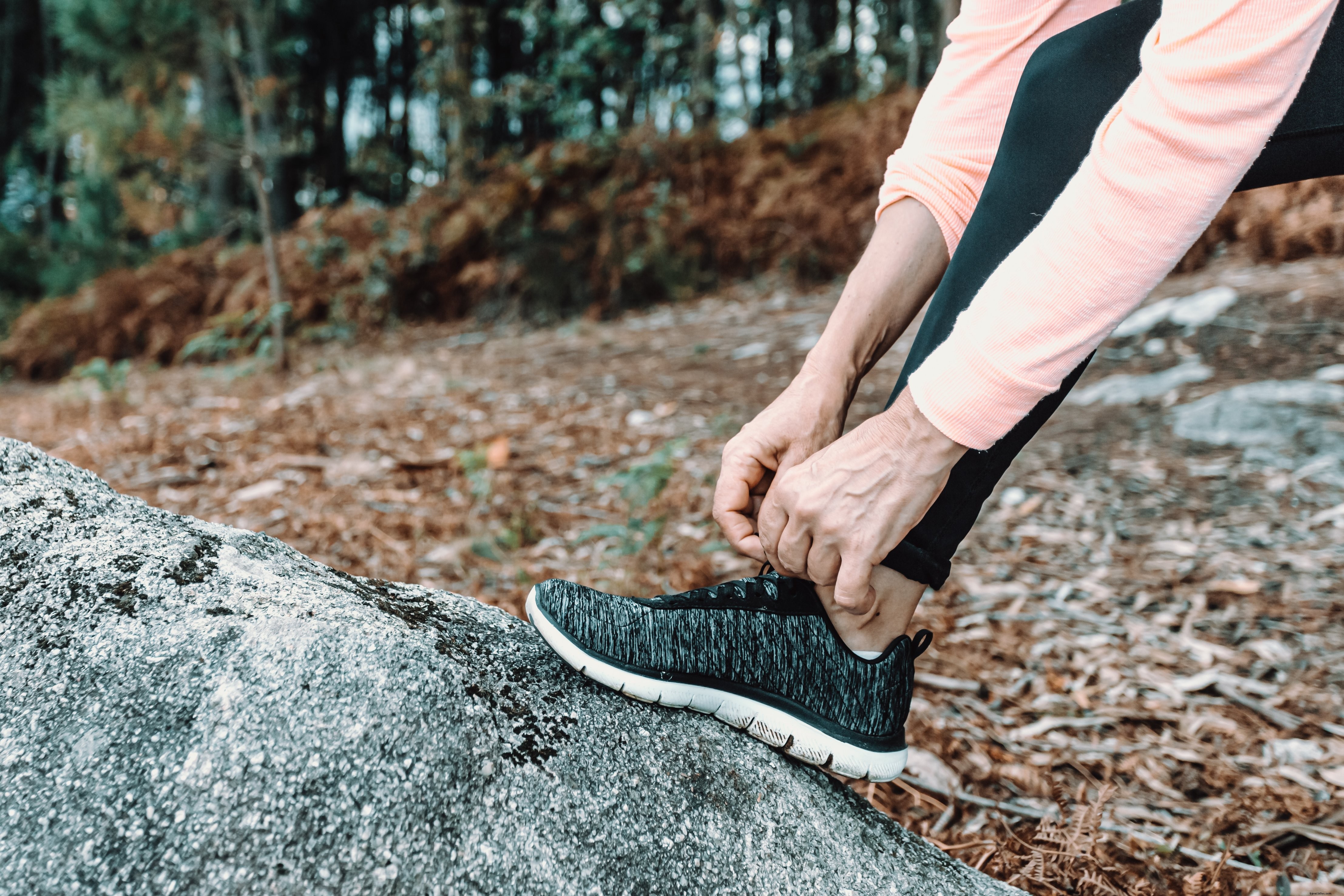 Close-Up: Hiker Adjusting Shoes on a Massive Rock – Stunning Adventure Photo
