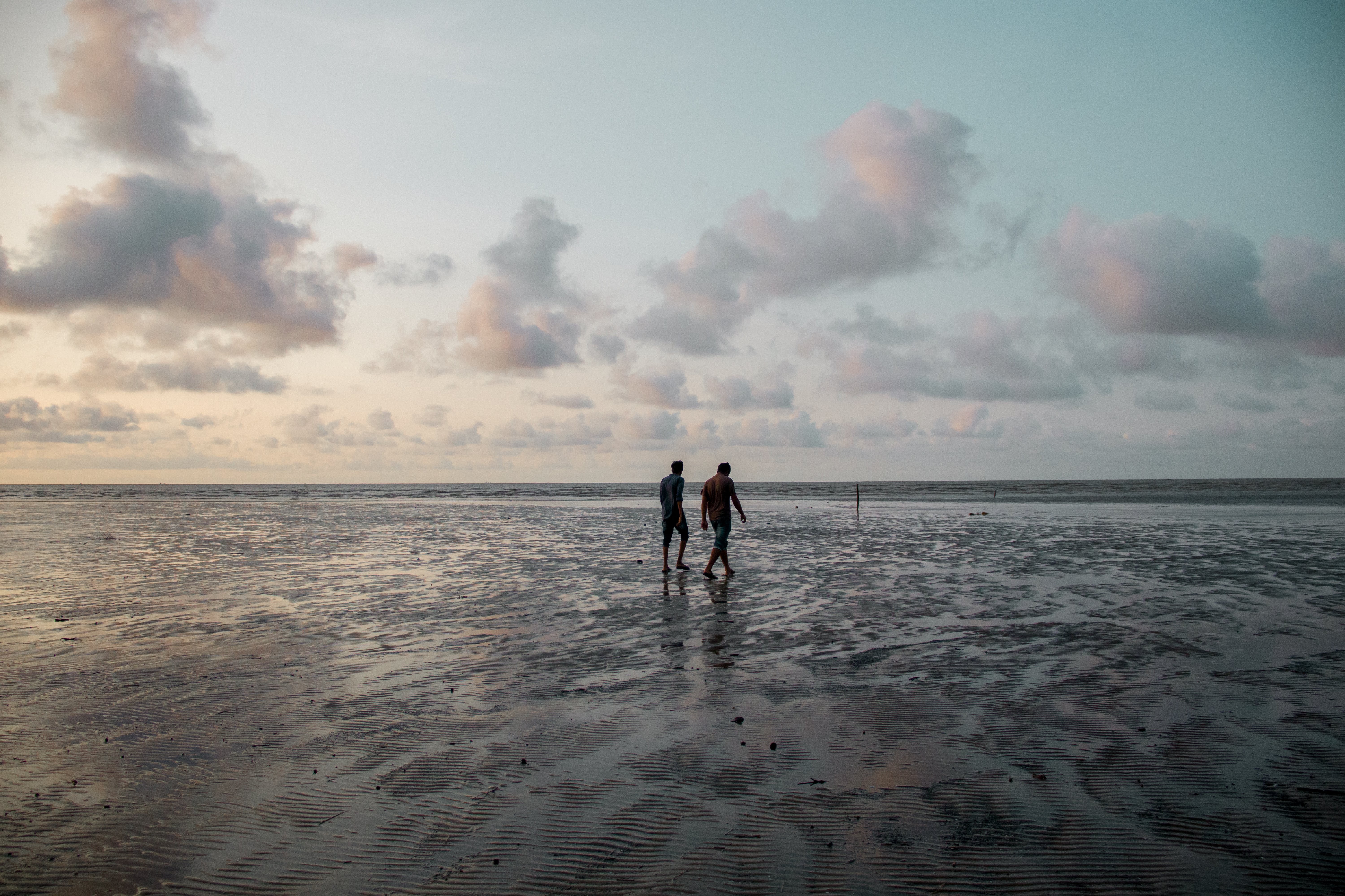 Stunning Sunset Beach Walk: Two People Strolling Along the Shore