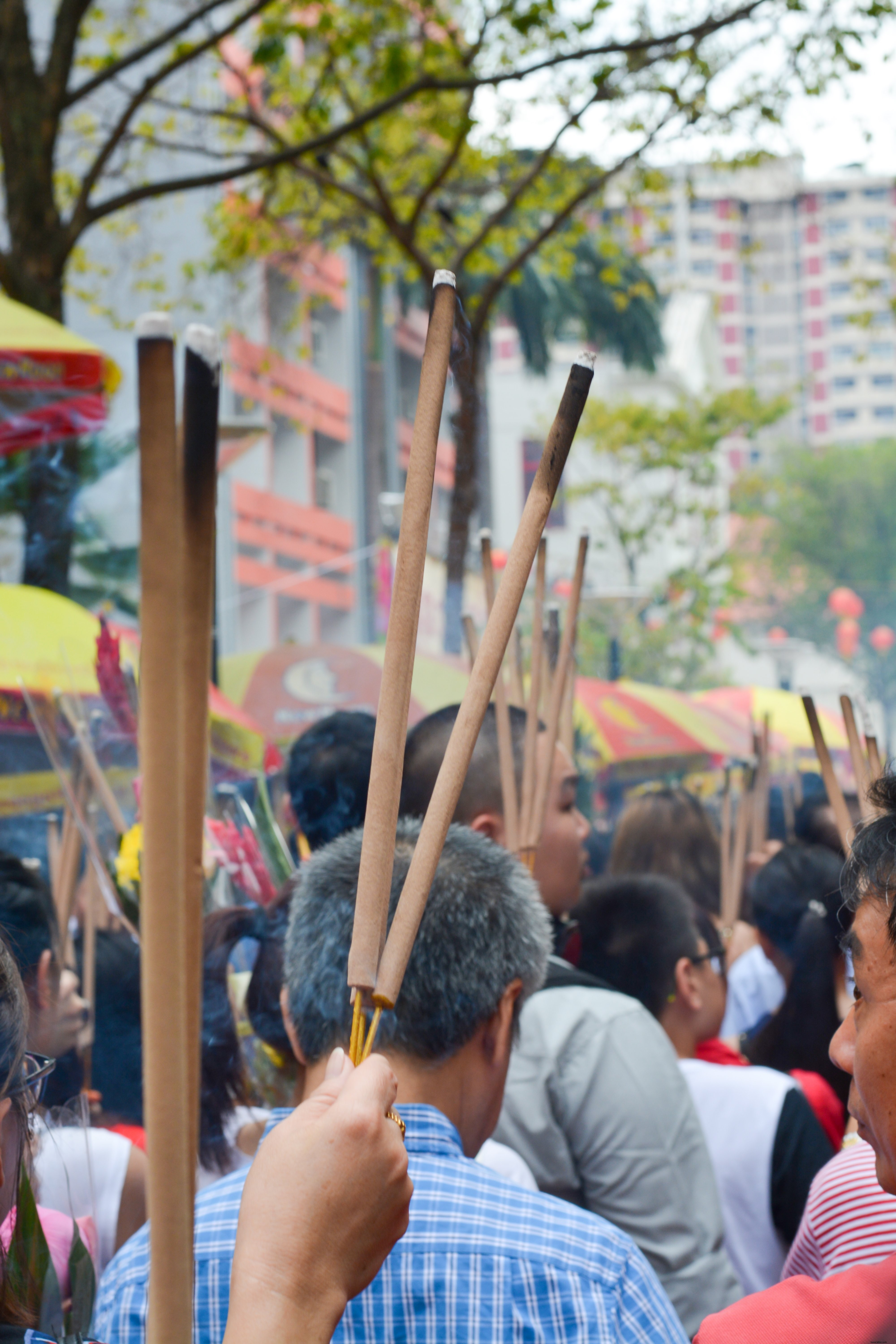 Bustling Street Scene: Crowds Holding Long Sticks with Charred Ends – Captivating Photo