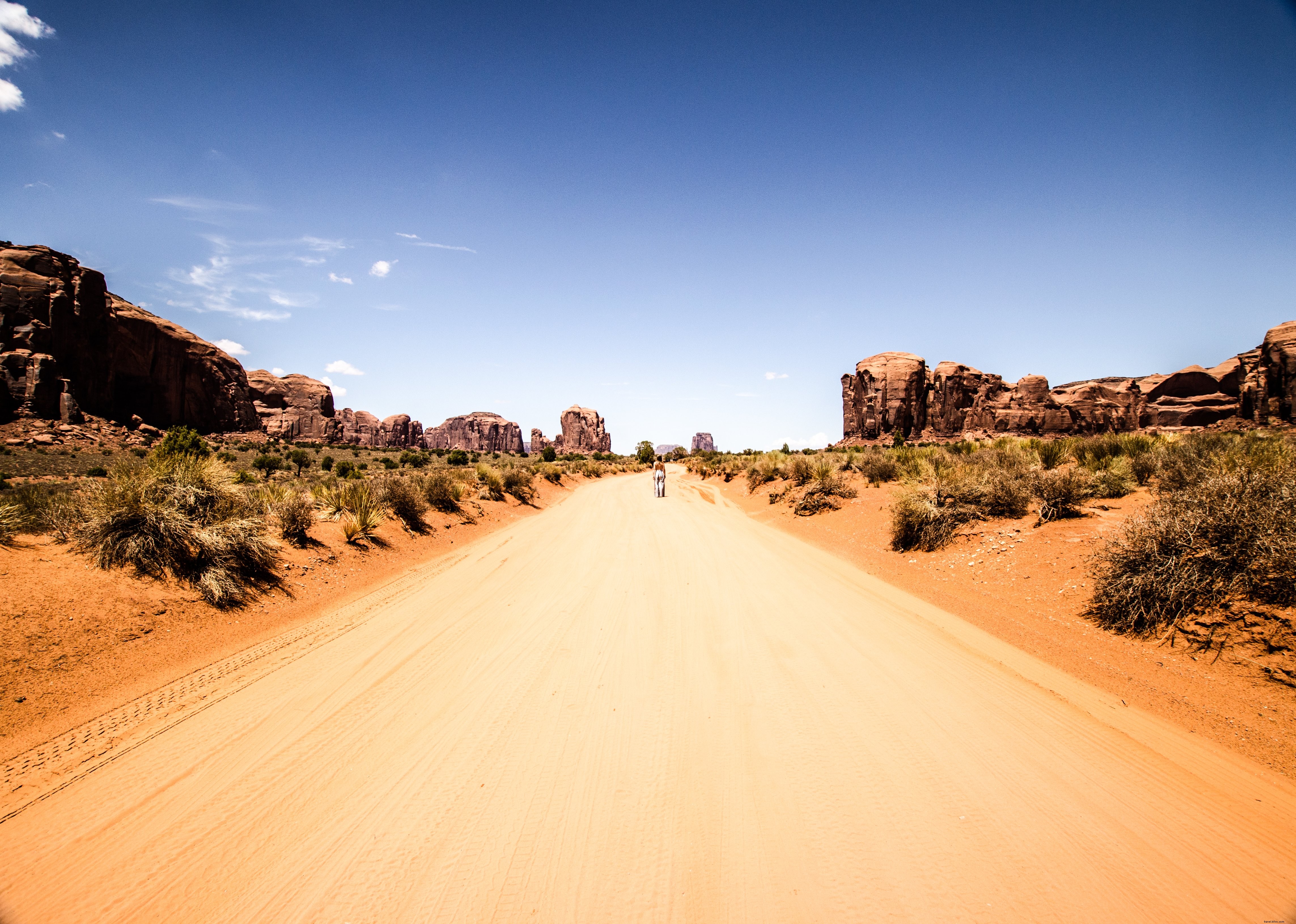 Solitary Figure on Desert Road Under Vast Blue Skies – Stunning Photo