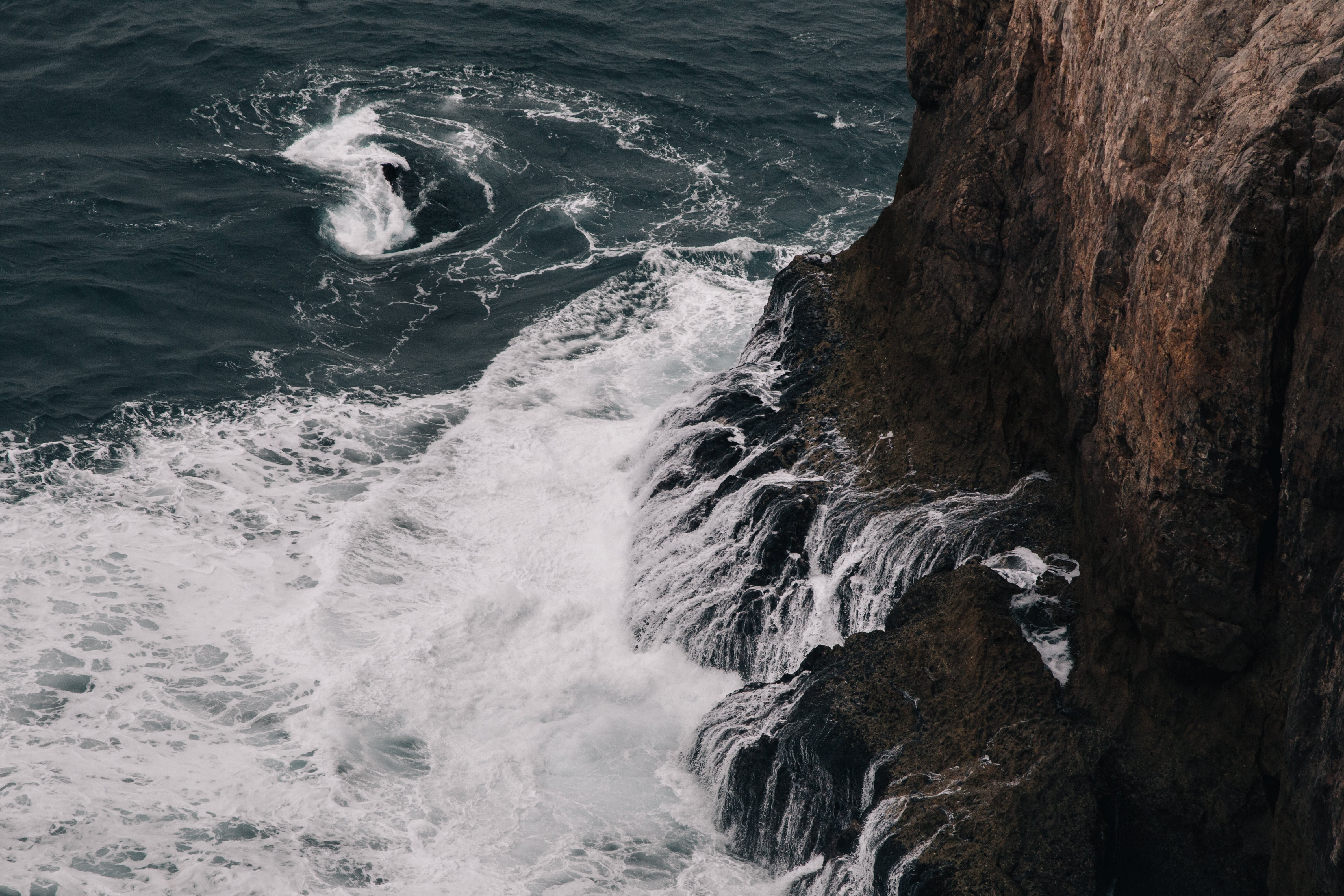 Stunning Photo: Foamy Waves Crashing Against a Rugged Cliff Base