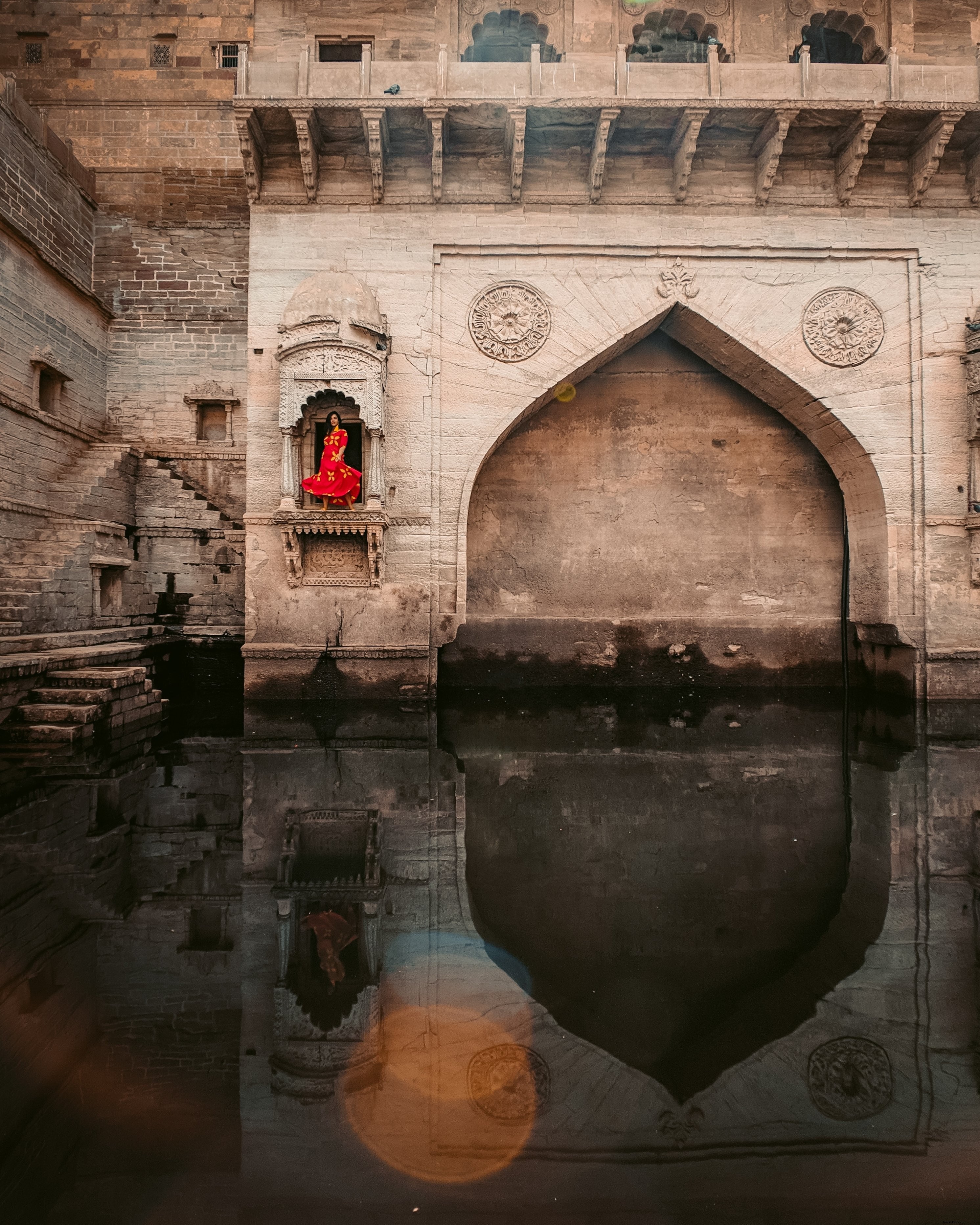 Elegant Woman in Red Dress Poses Before Ornate Monument – Stunning Photo
