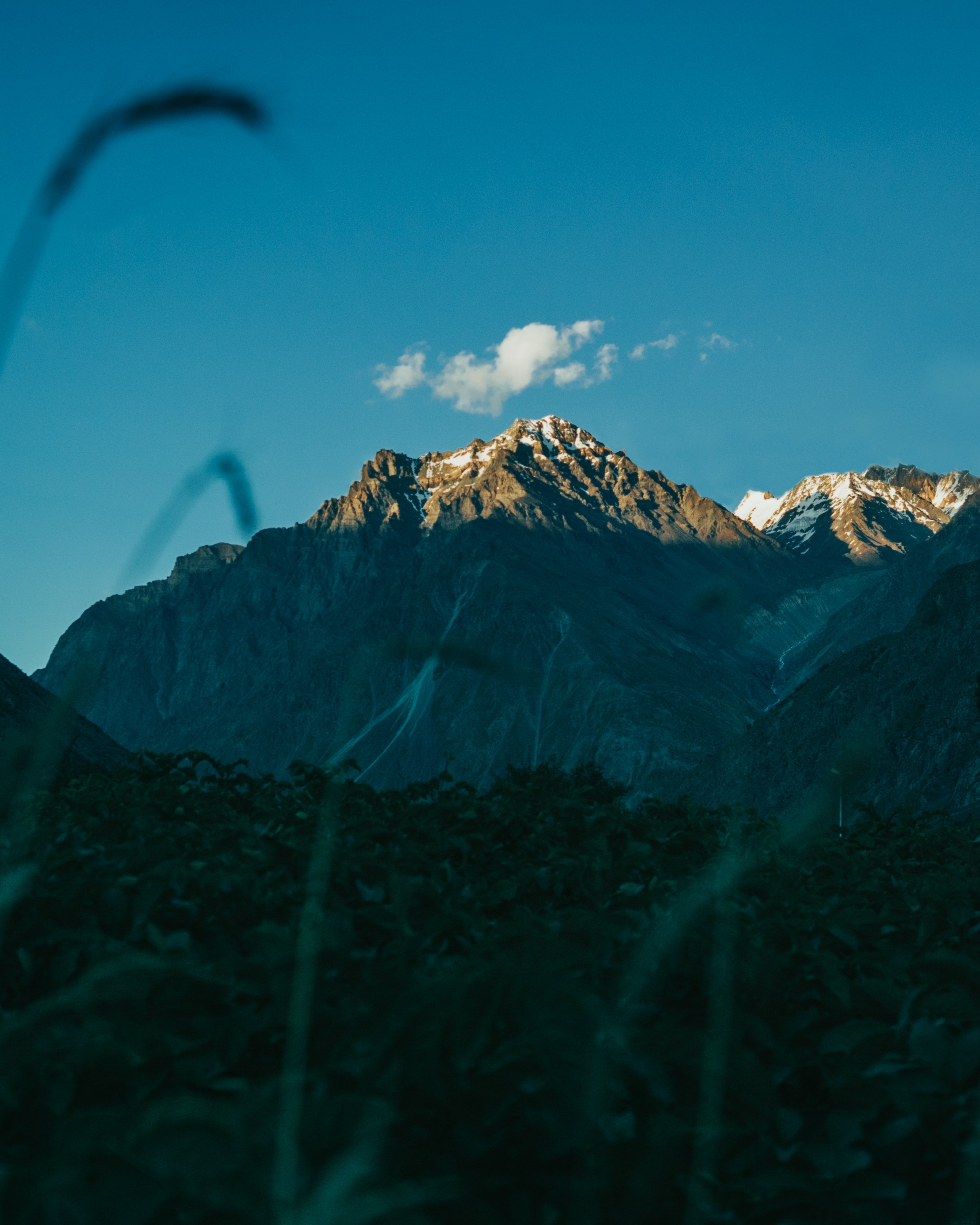 Stunning Photo: Lone Cloud Hovers Over Majestic Mountain Peak