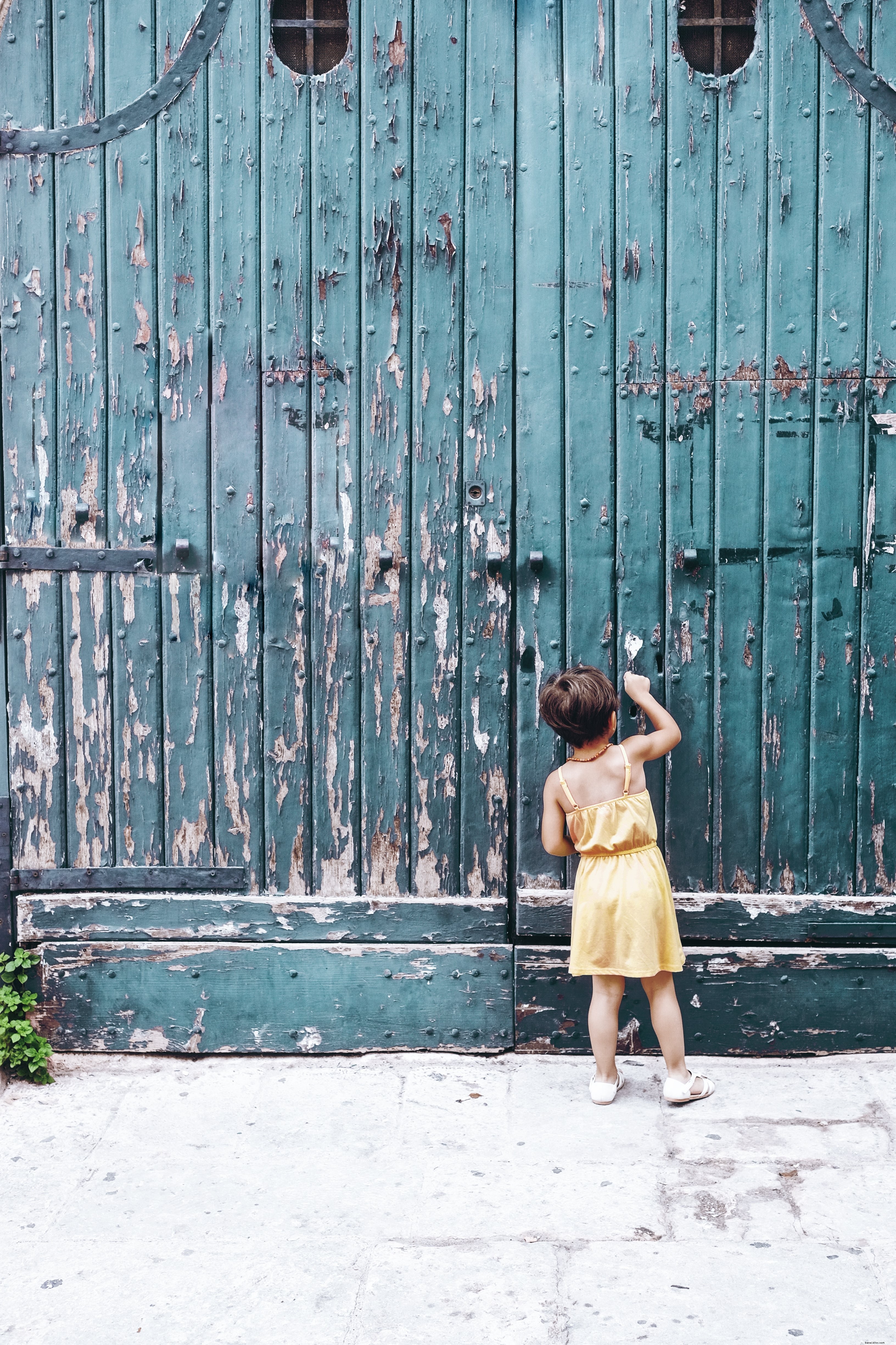 Captivating Photo: Young Person Knocking on Striking Large Blue Doorway