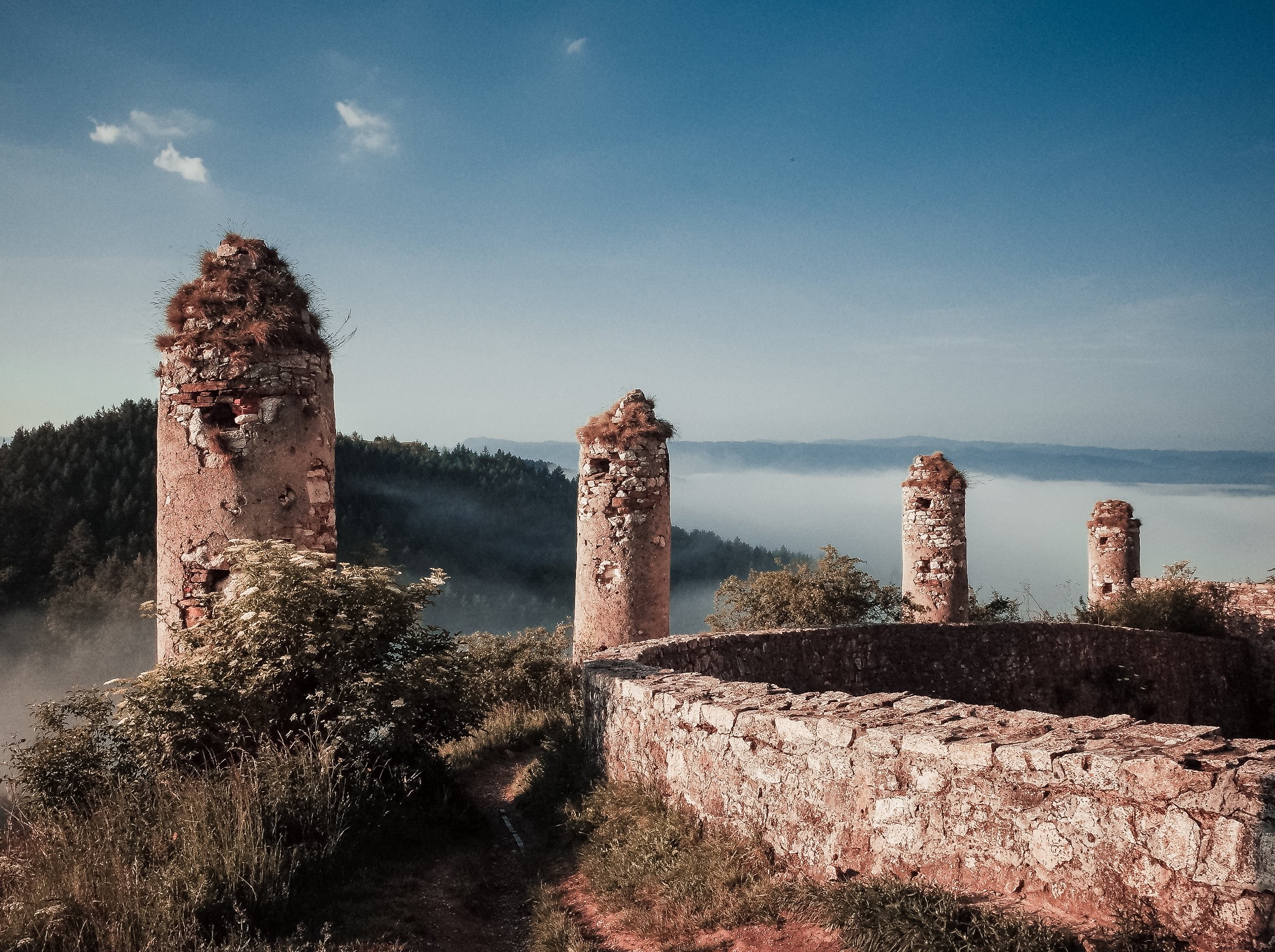 Serene Grass-Covered Ancient Ruins Overlooking Majestic Mountain Peaks