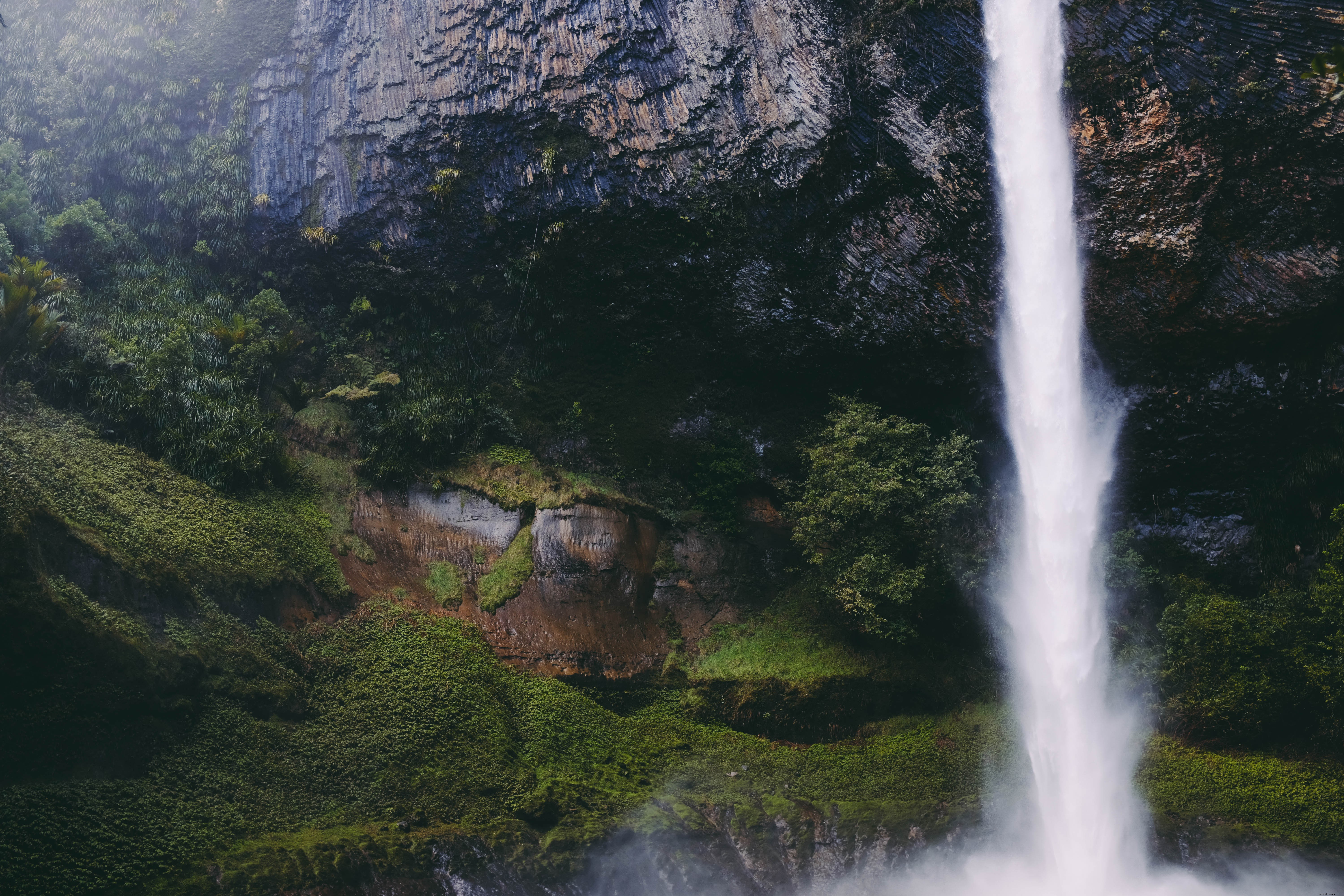 Stunning Waterfall Cascading from Rock Formations over Lush Green Grass