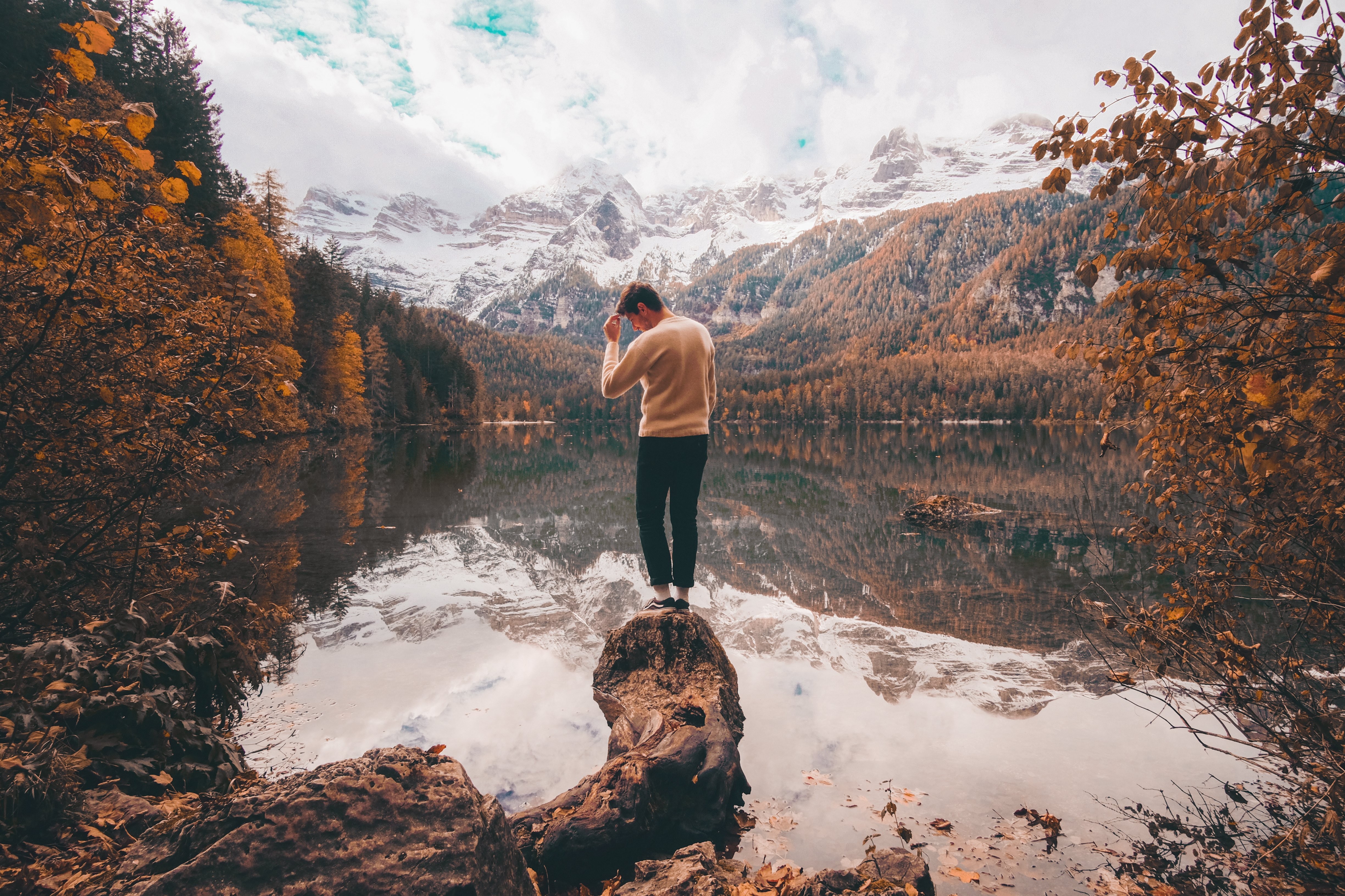 Breathtaking Photo: Person Amidst Vibrant Fall Foliage and Snow-Capped Mountains