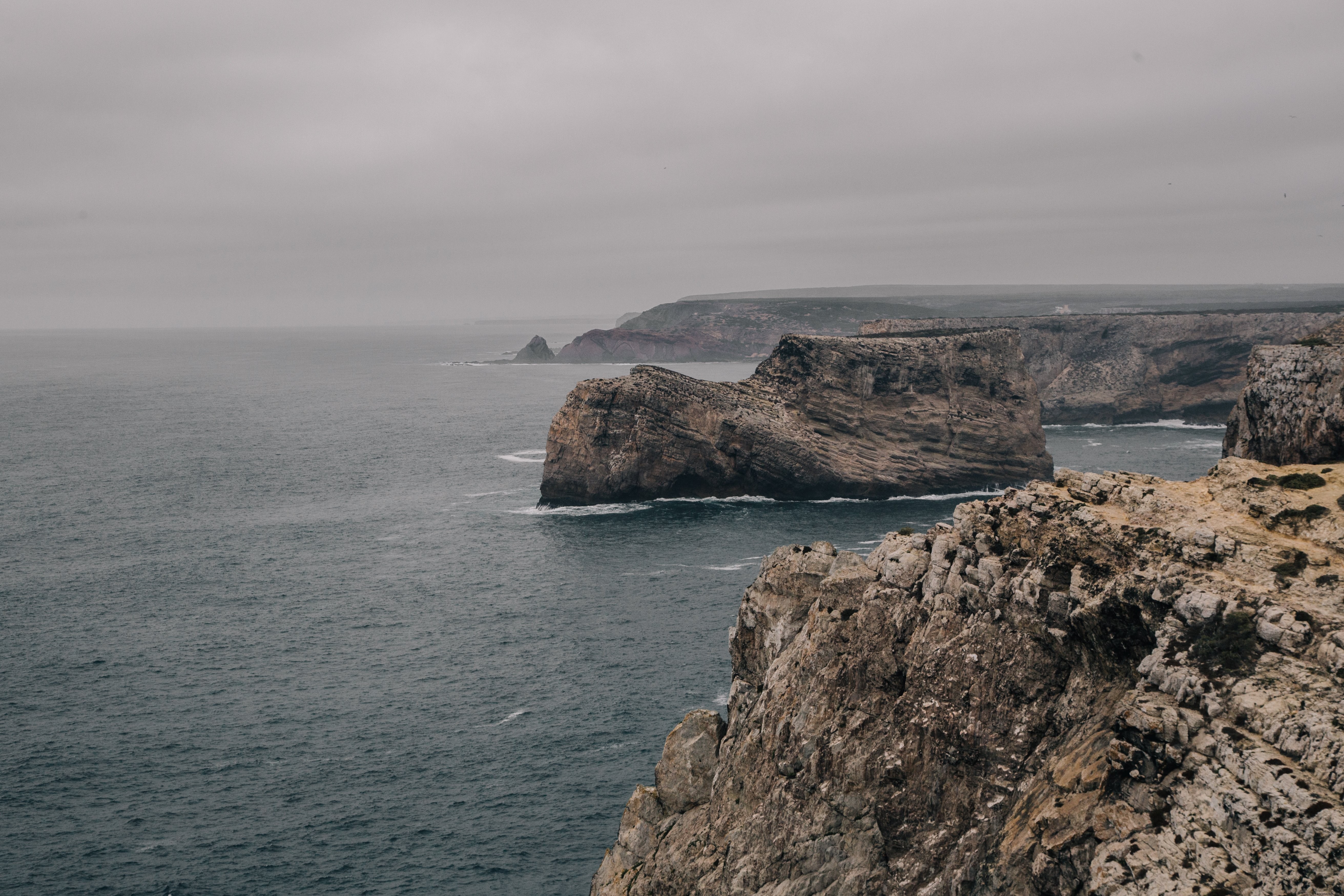 Stunning Rocky Cliffs Receding from the Cold Grey Sea – Captivating Photo
