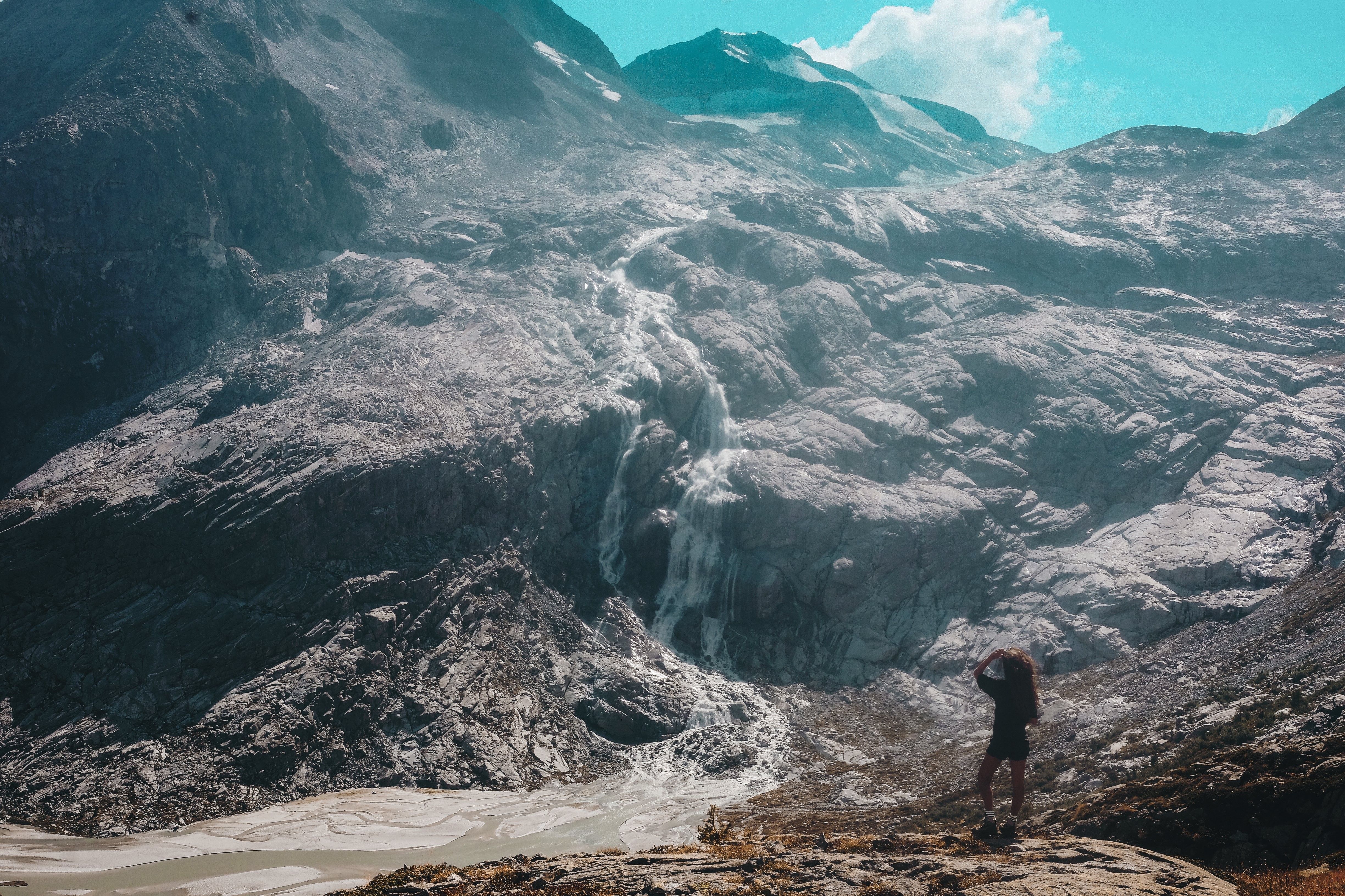 Breathtaking Mountainside Waterfall: Person Gazes in Awe – Stunning Photo