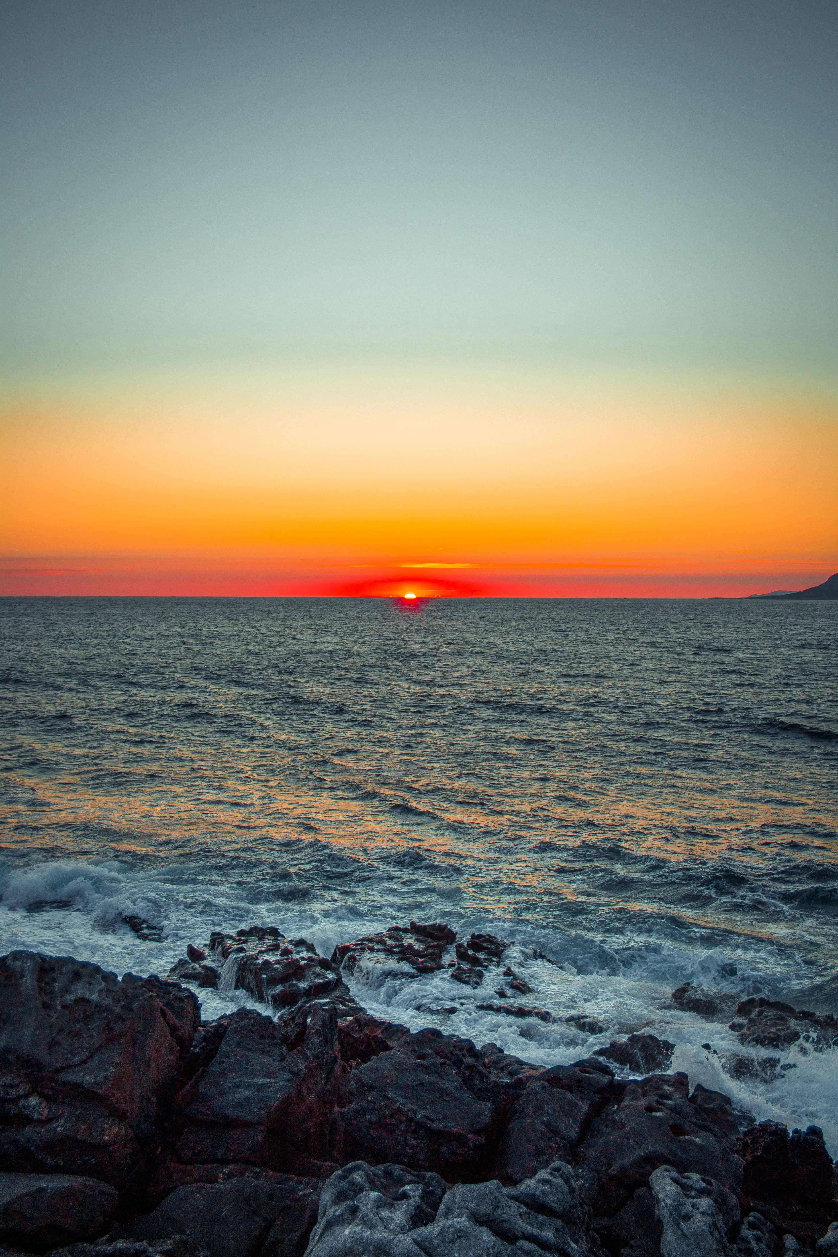 Breathtaking Last Moments of a Sunset Over the Rocky Shore – Stunning Photo